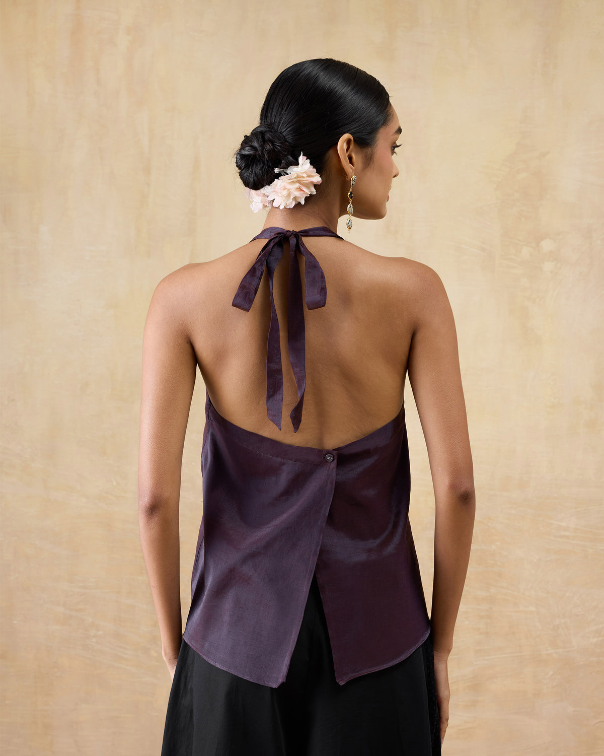 Back of a plum metallic halter top with an open back and neck ties.