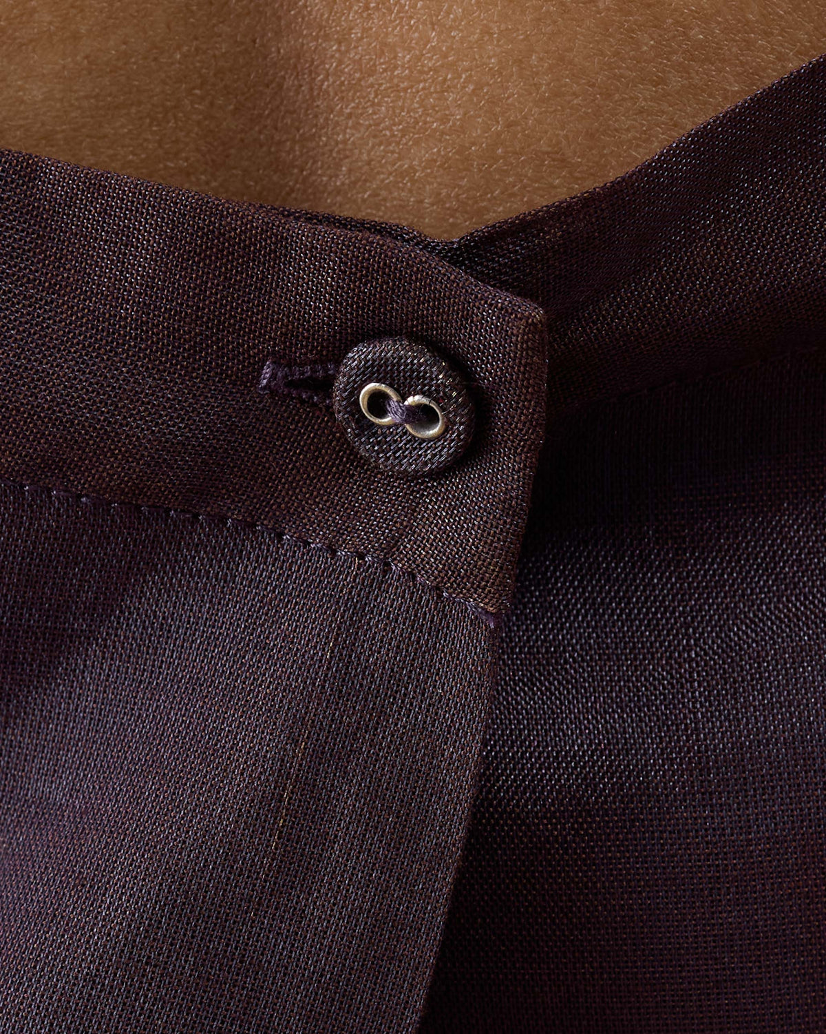 Close-up of a plum metallic top with a fabric-covered button.