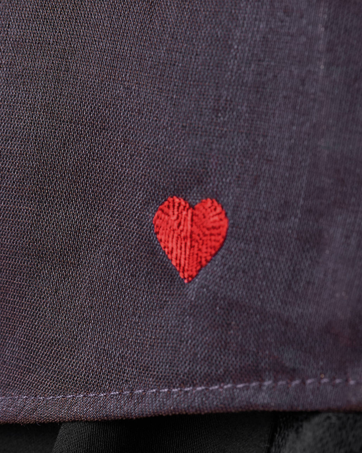 Close-up of a plum metallic top with a small red embroidered heart.