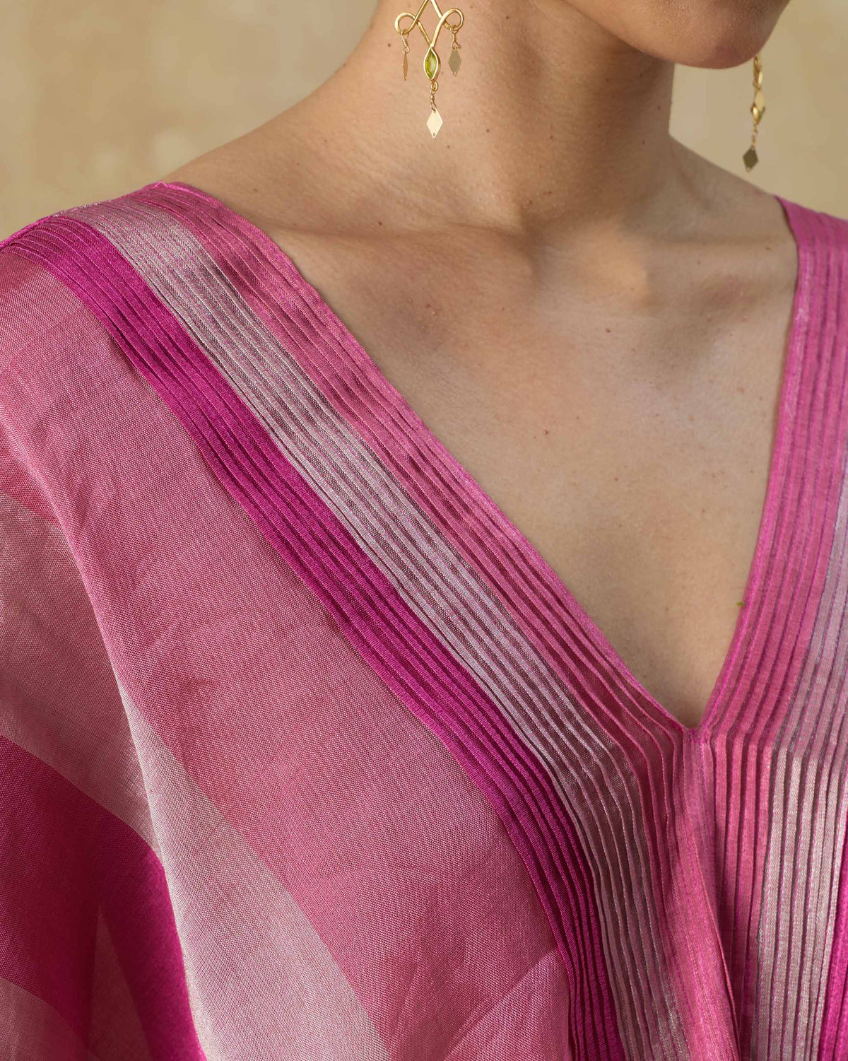 Close-up of a pink striped Jhilmil Kaftan V-neck with pleated trim.