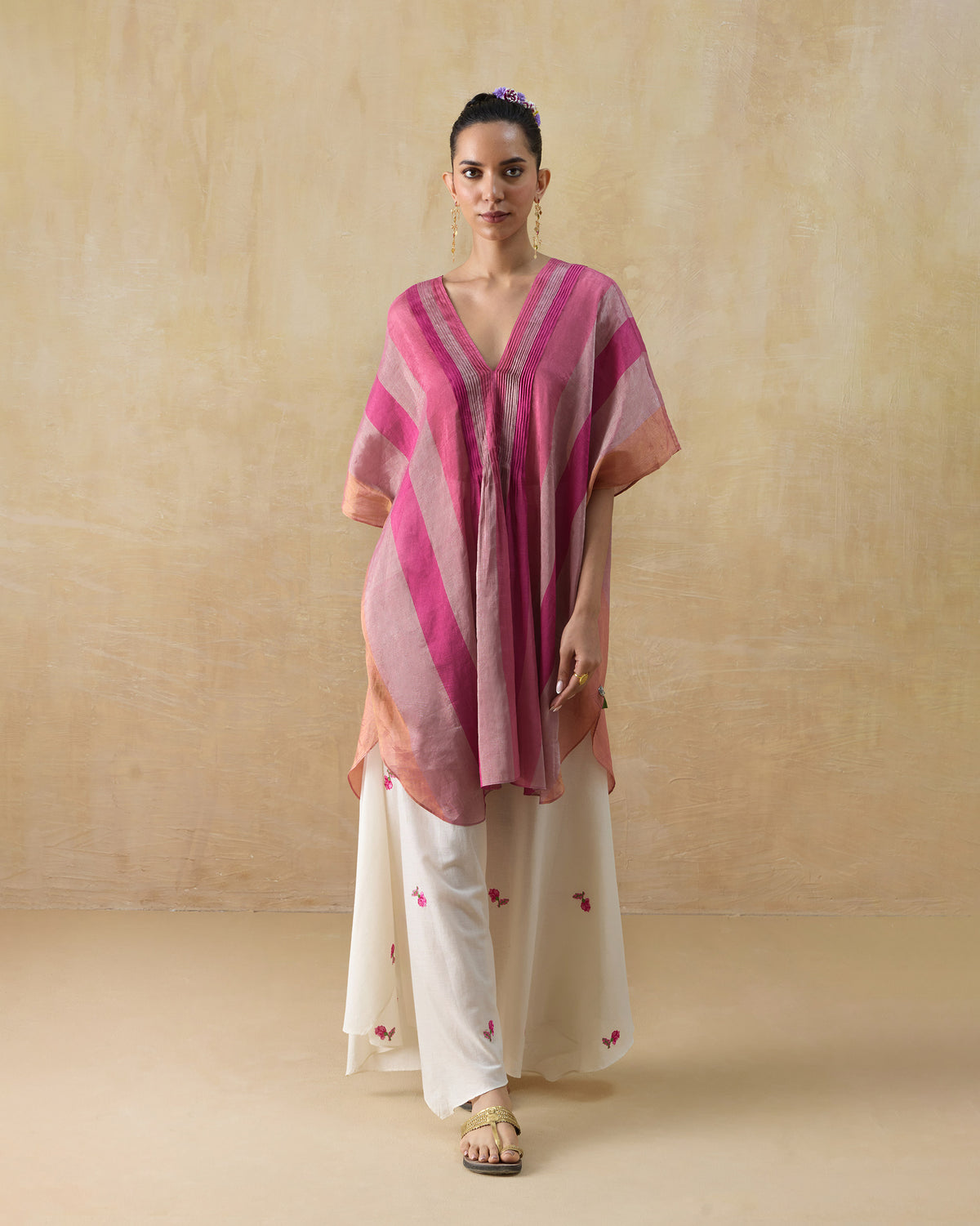 Person wearing a pink striped Jhilmil Kaftan with a deep V-neck and curved hem.