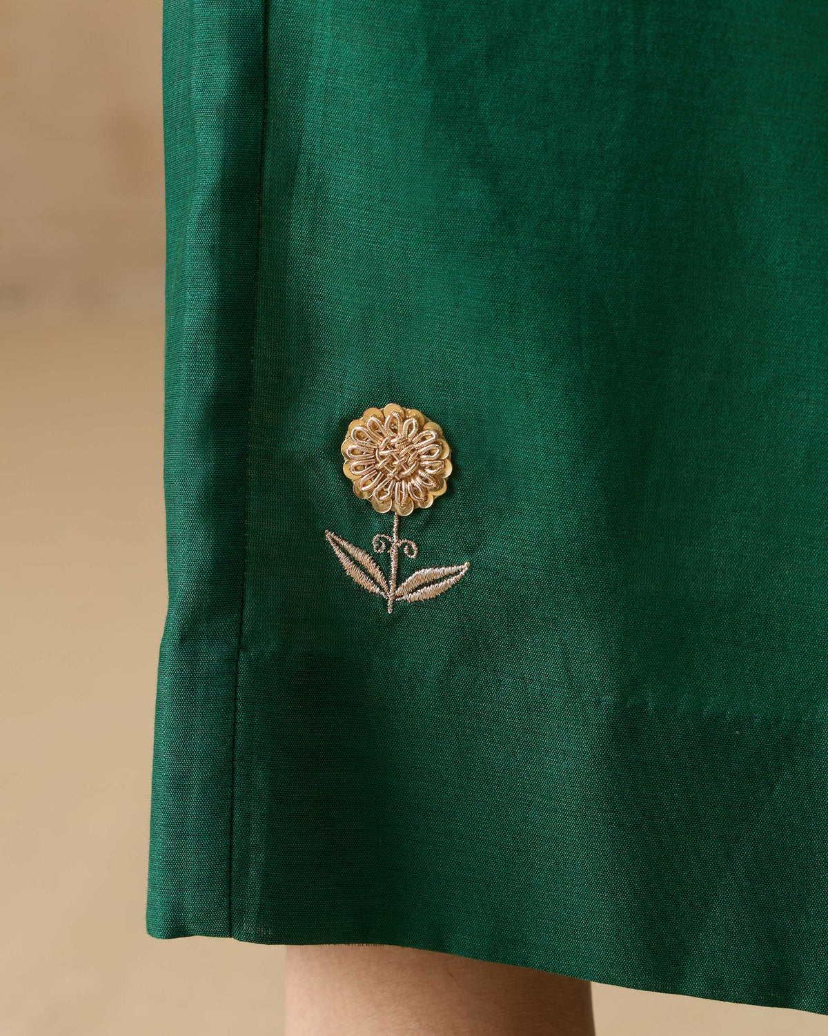 Close-up of gold floral embroidery on emerald green Basic pyjamas.