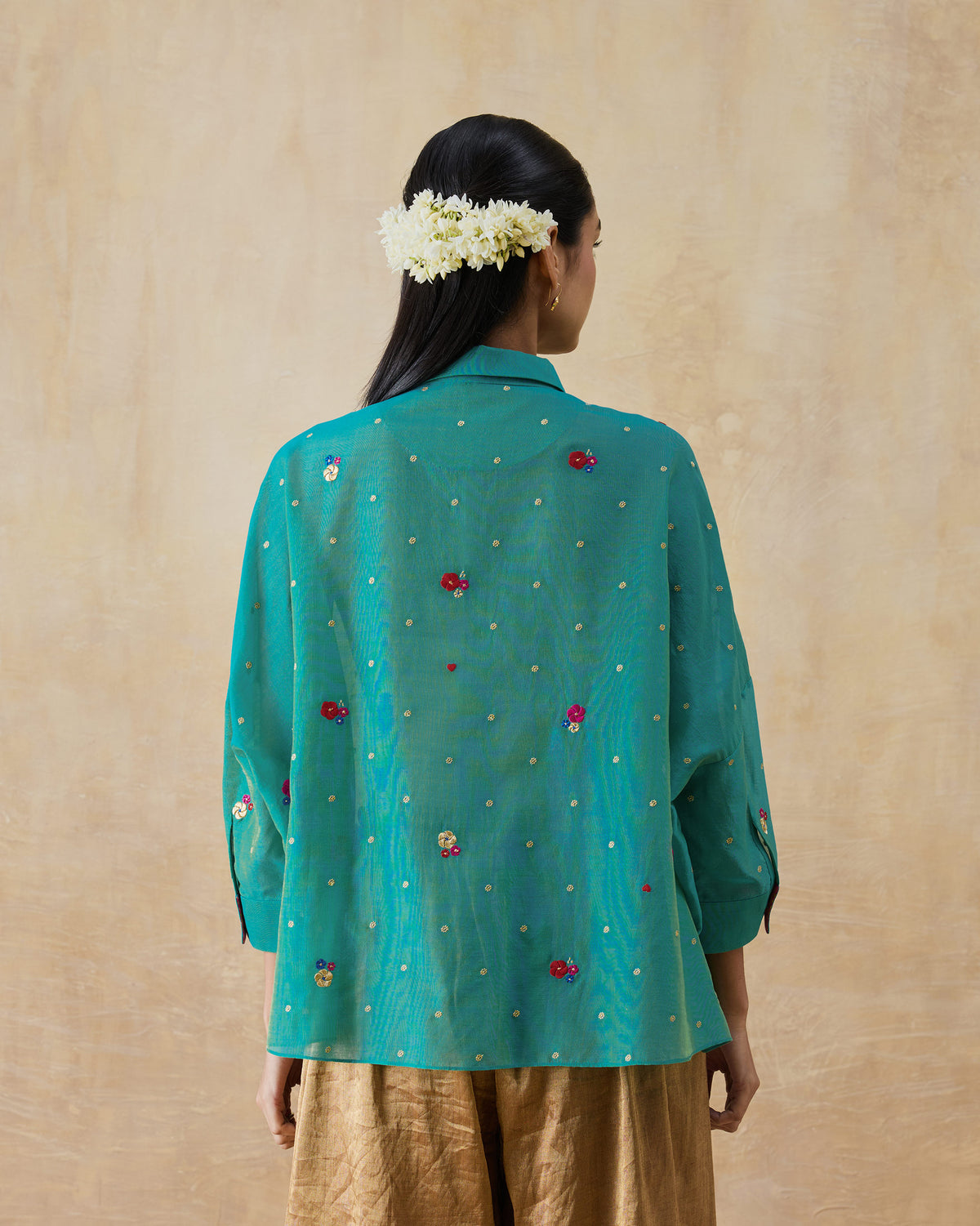 Back of an aqua Boxy shirt with floral embroidery and gold dots.