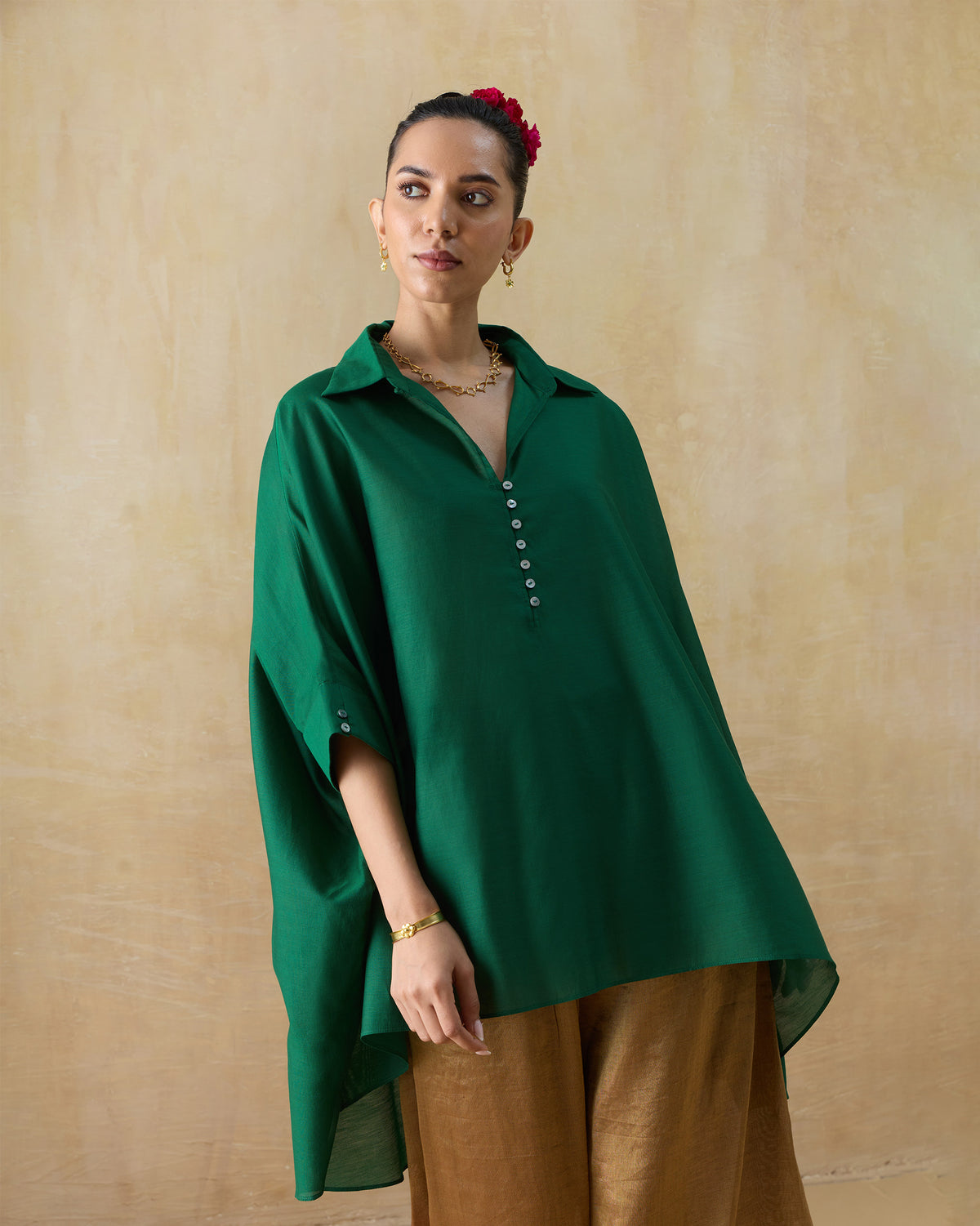 Person wearing a loose emerald green Hala tunic with wide three-quarter sleeves.