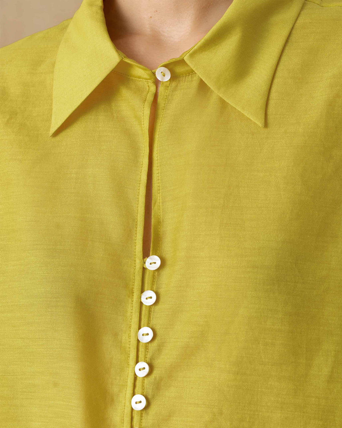 Close-up of a chartreuse tunic collar with white buttons.
