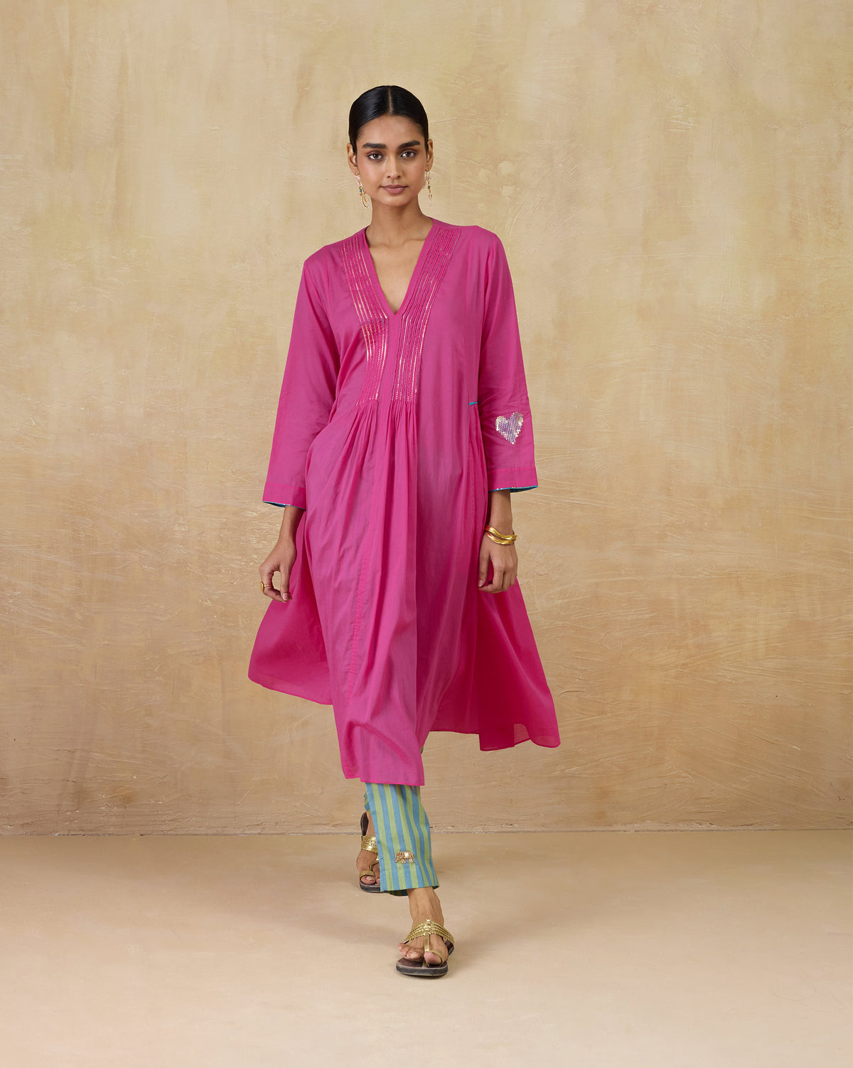 Person wearing a bright pink Pintuck kurta with a sequin heart on the sleeve.