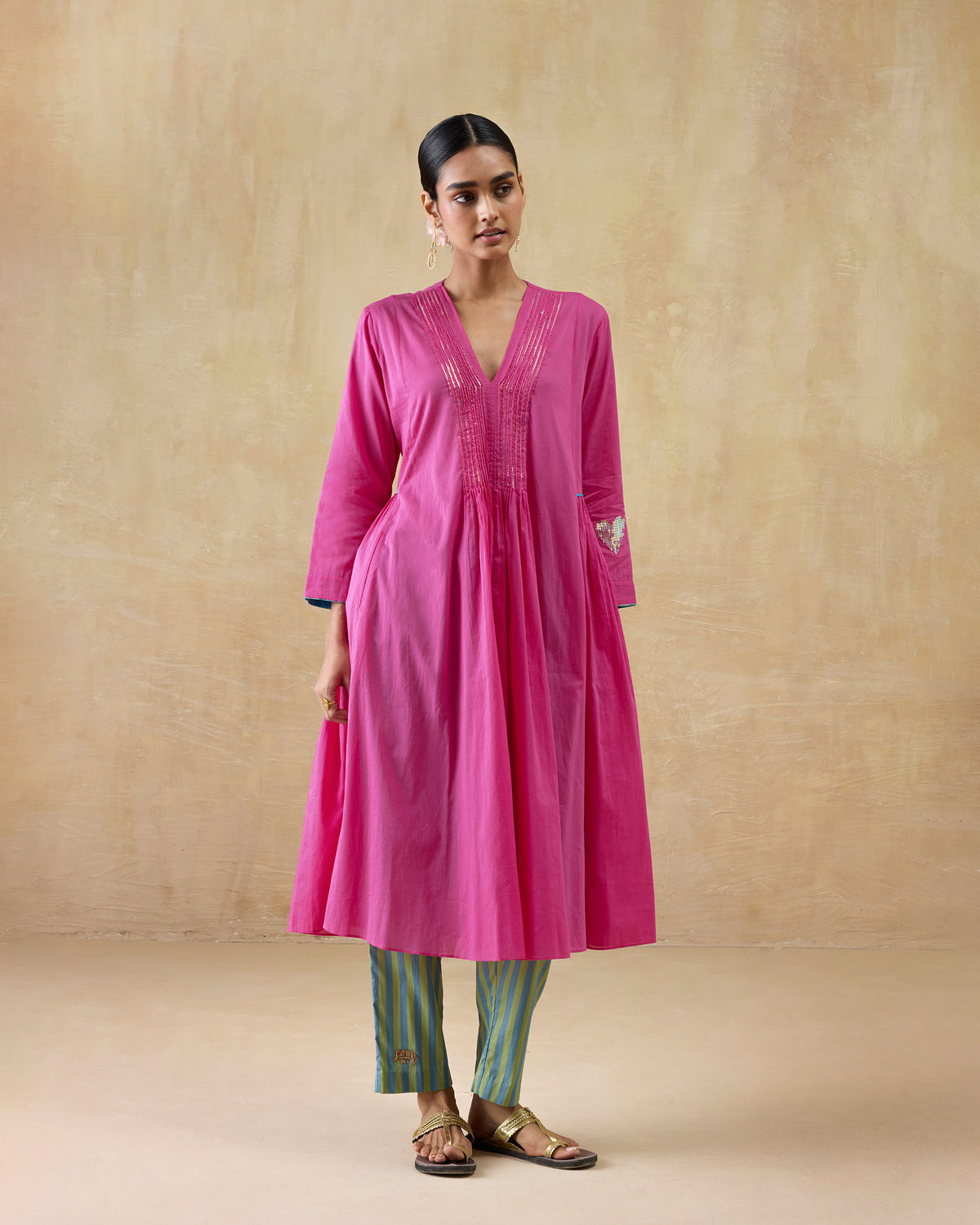 Person wearing a bright pink Pintuck kurta with gold pintucks at the neck.