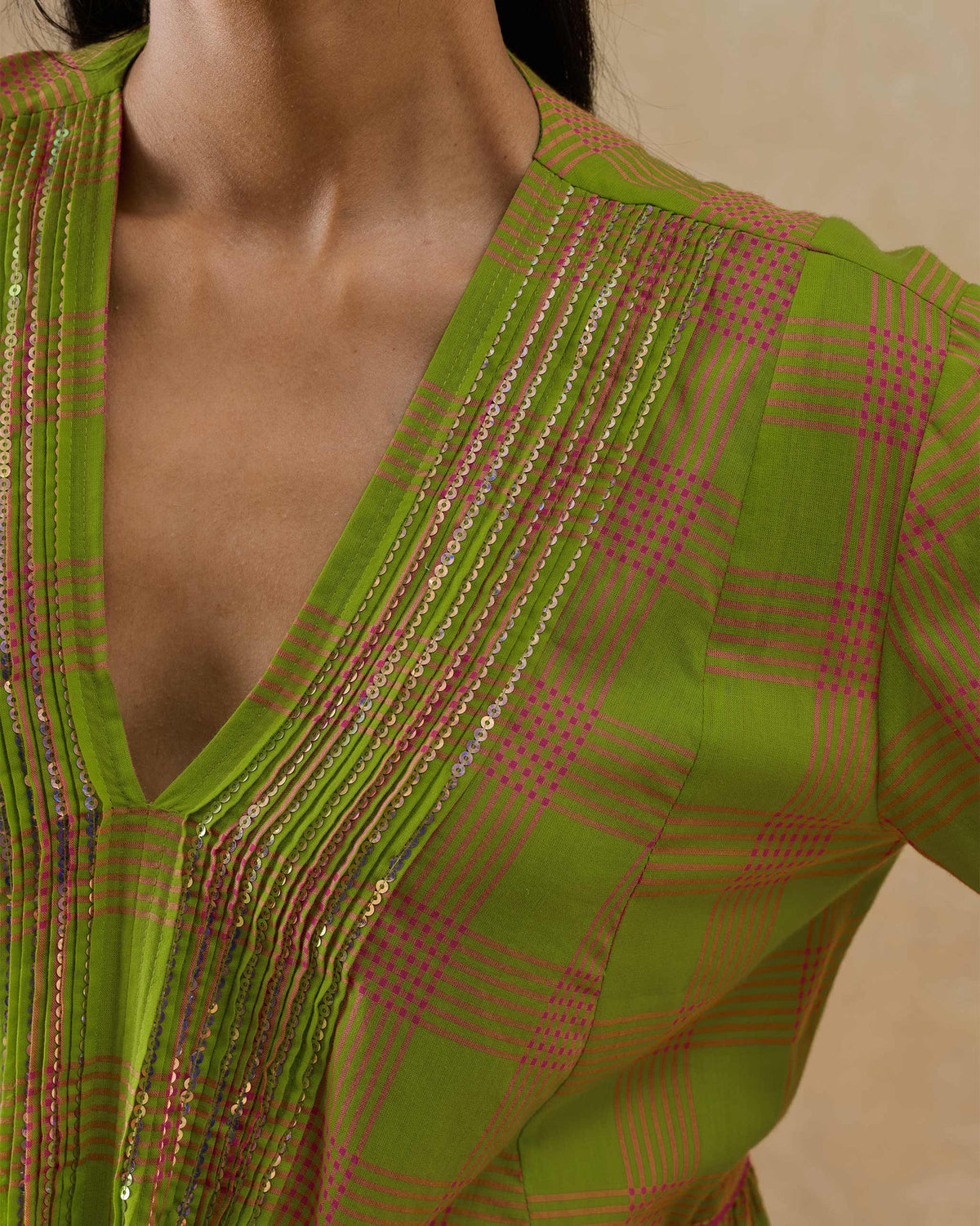 Close-up of gold sequin trim on the V-neck of the lime green Pintuck kurta.