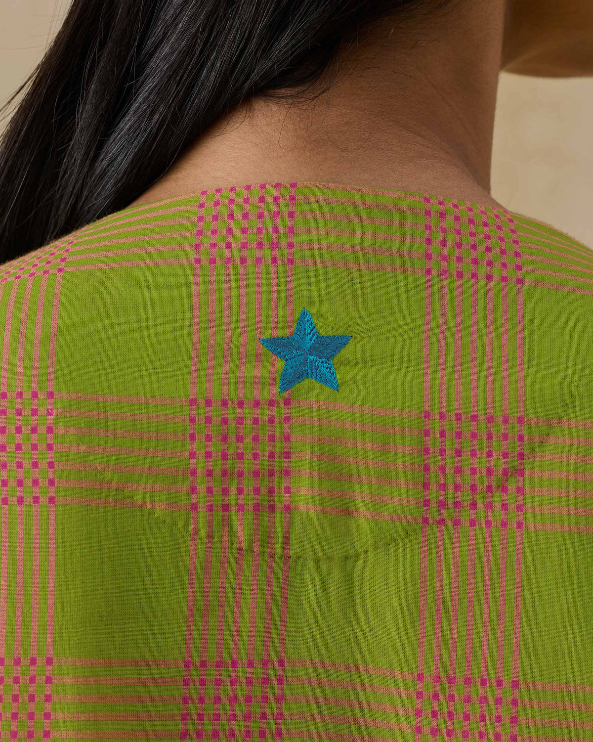 Close-up of a blue embroidered star on the back of the Pintuck kurta.