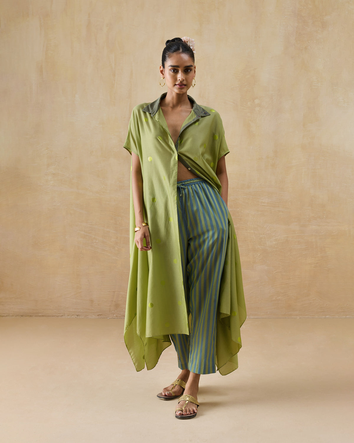 Person wearing an open green polka-dot kaftan with short sleeves.