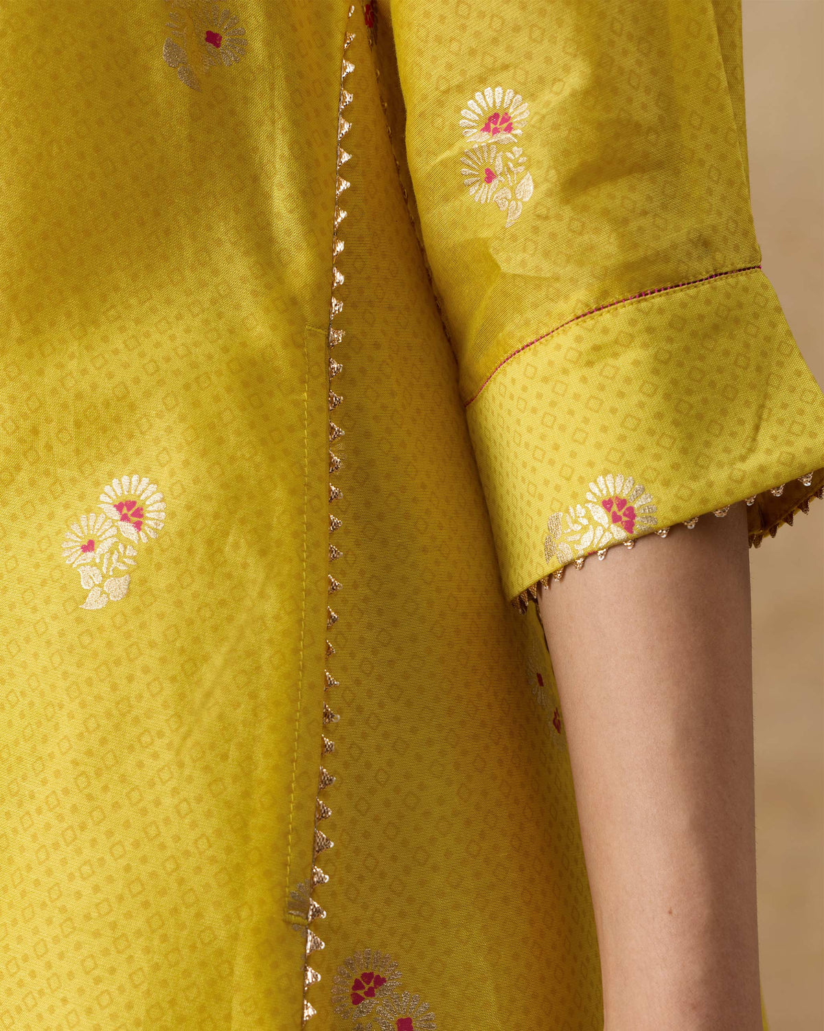 Close-up of the gold lace trim and cuffed sleeve on a chartreuse Viva kurta.