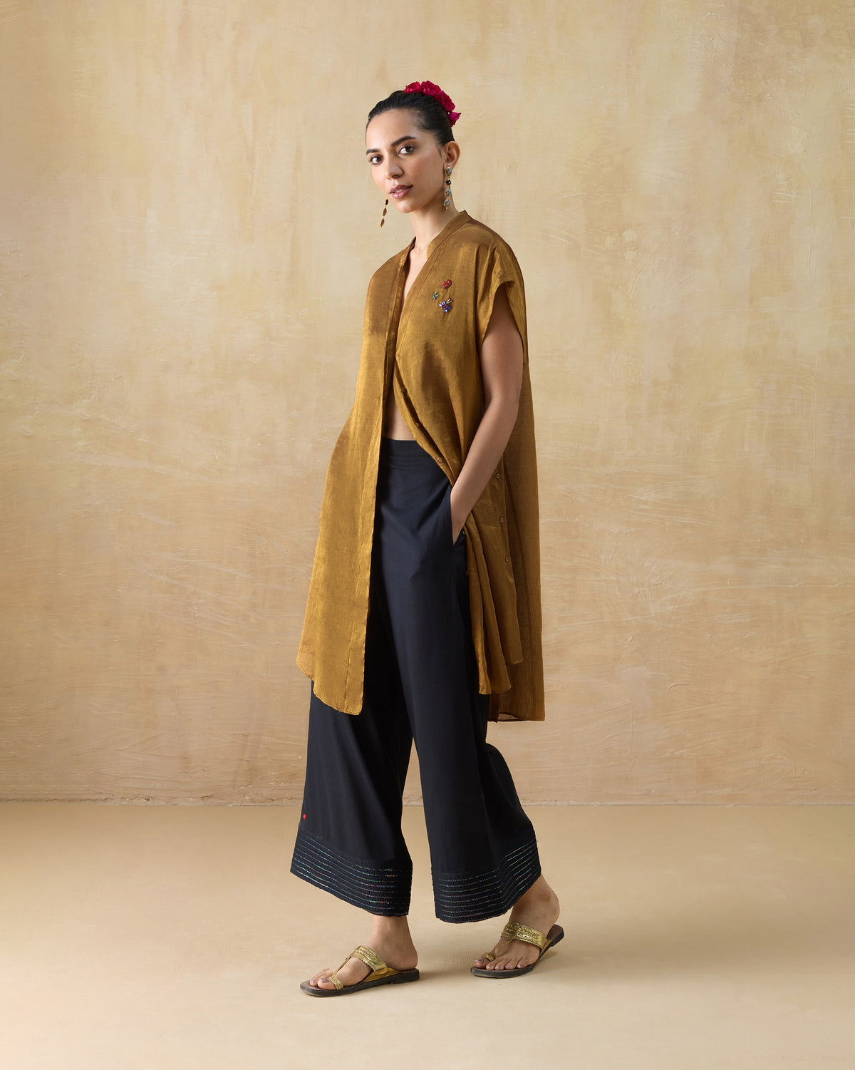 Person wearing a gold metallic Tango kaftan with a band collar and open front.