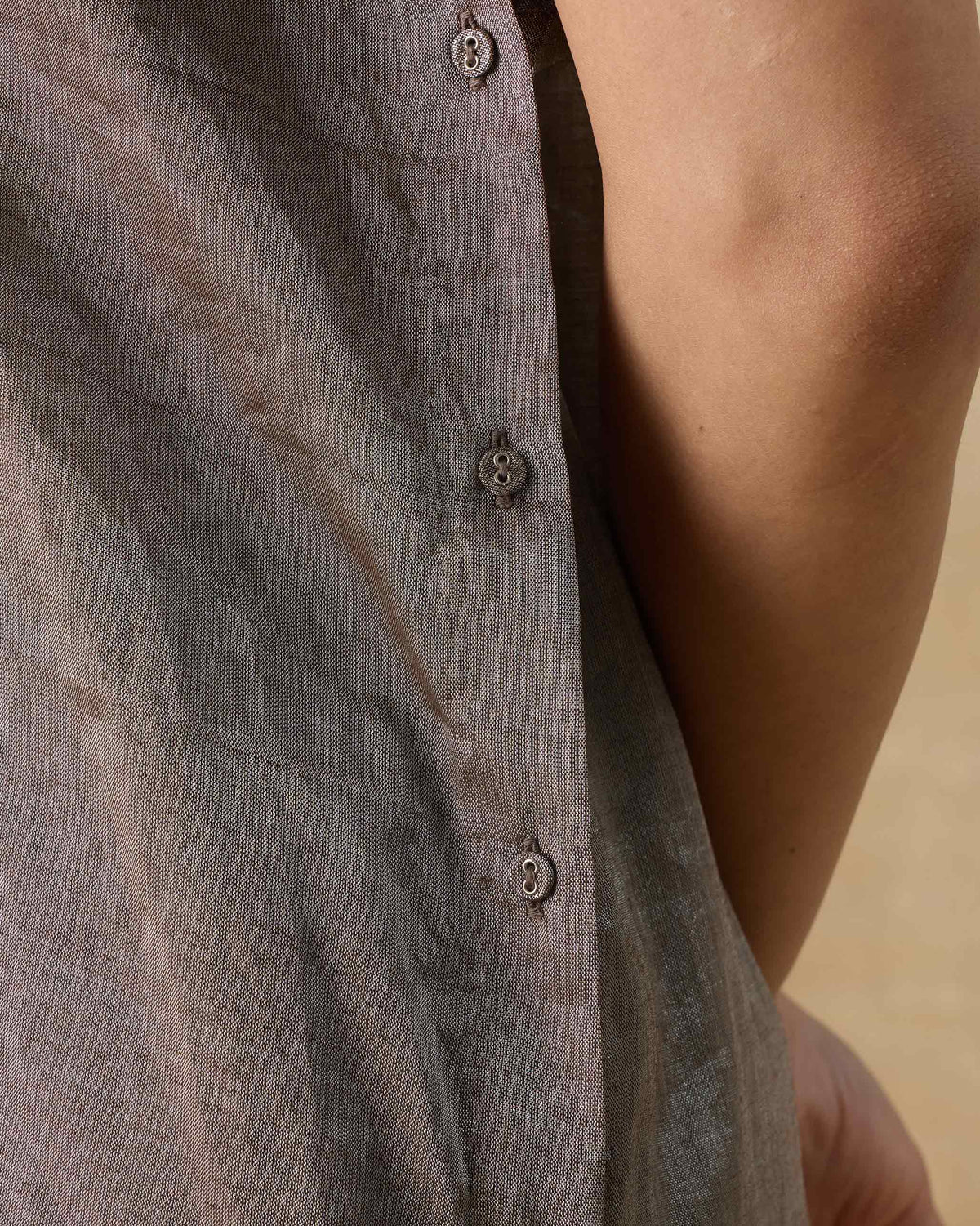 Close-up of a silver metallic kaftan with a side button placket.