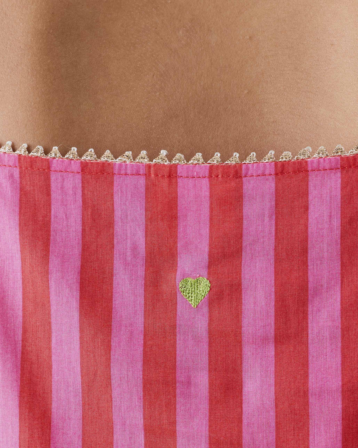 Close-up of a green heart on a red and berry striped Mist Camisole.