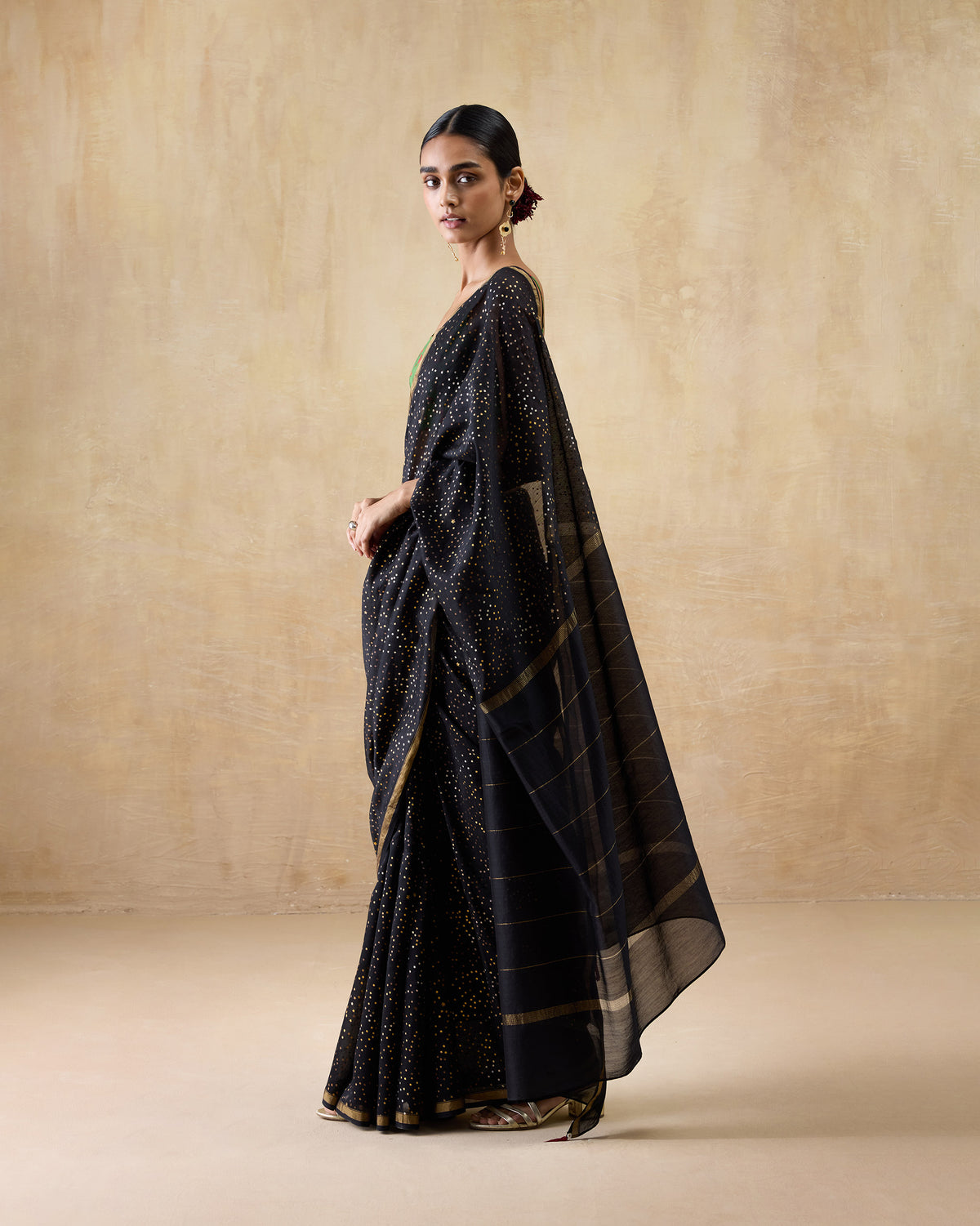 Side view of a black and gold Riverbank sari showing the speckled drape and striped pallu.