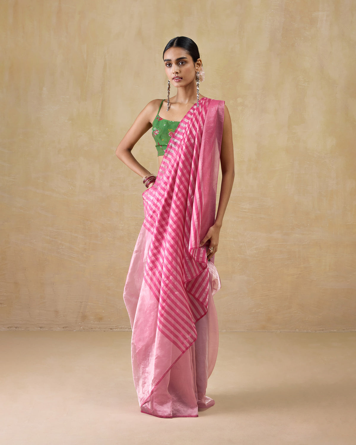 Person wearing a blush pink metallic tissue Blush sari with a striped pallu.