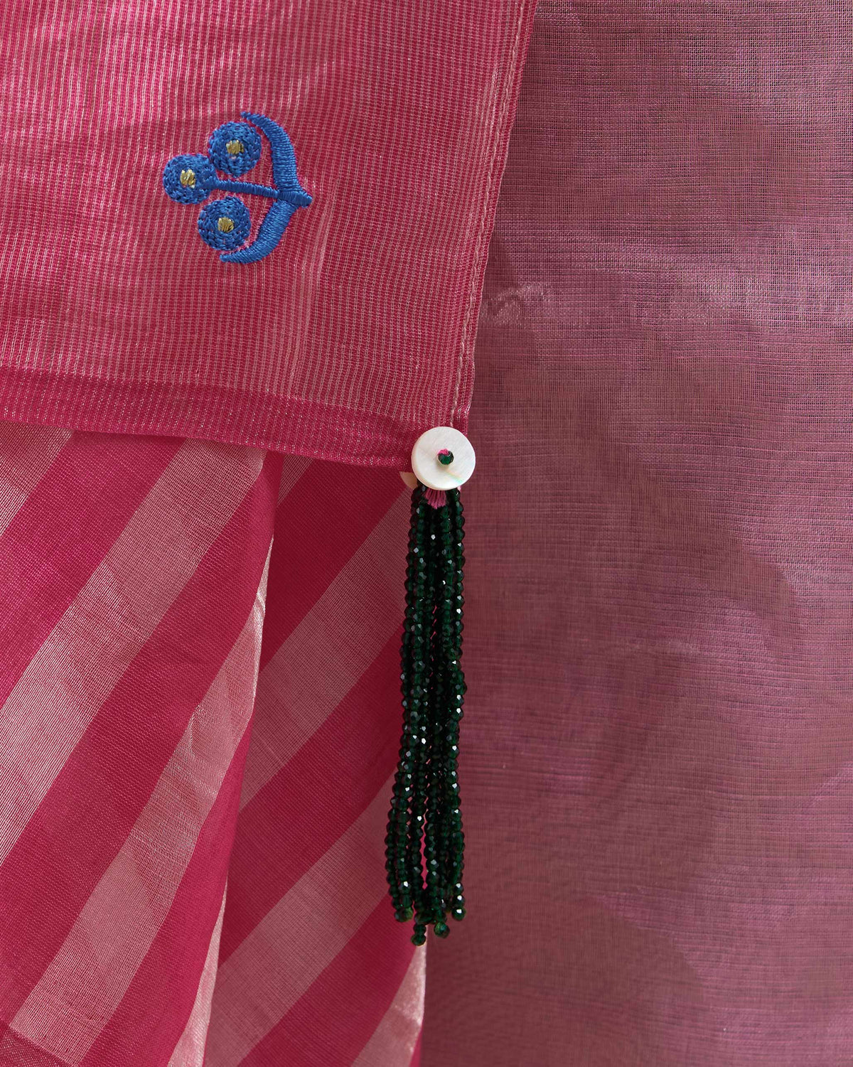 Close-up of a blue motif and green bead tassel on a blush pink Blush sari.