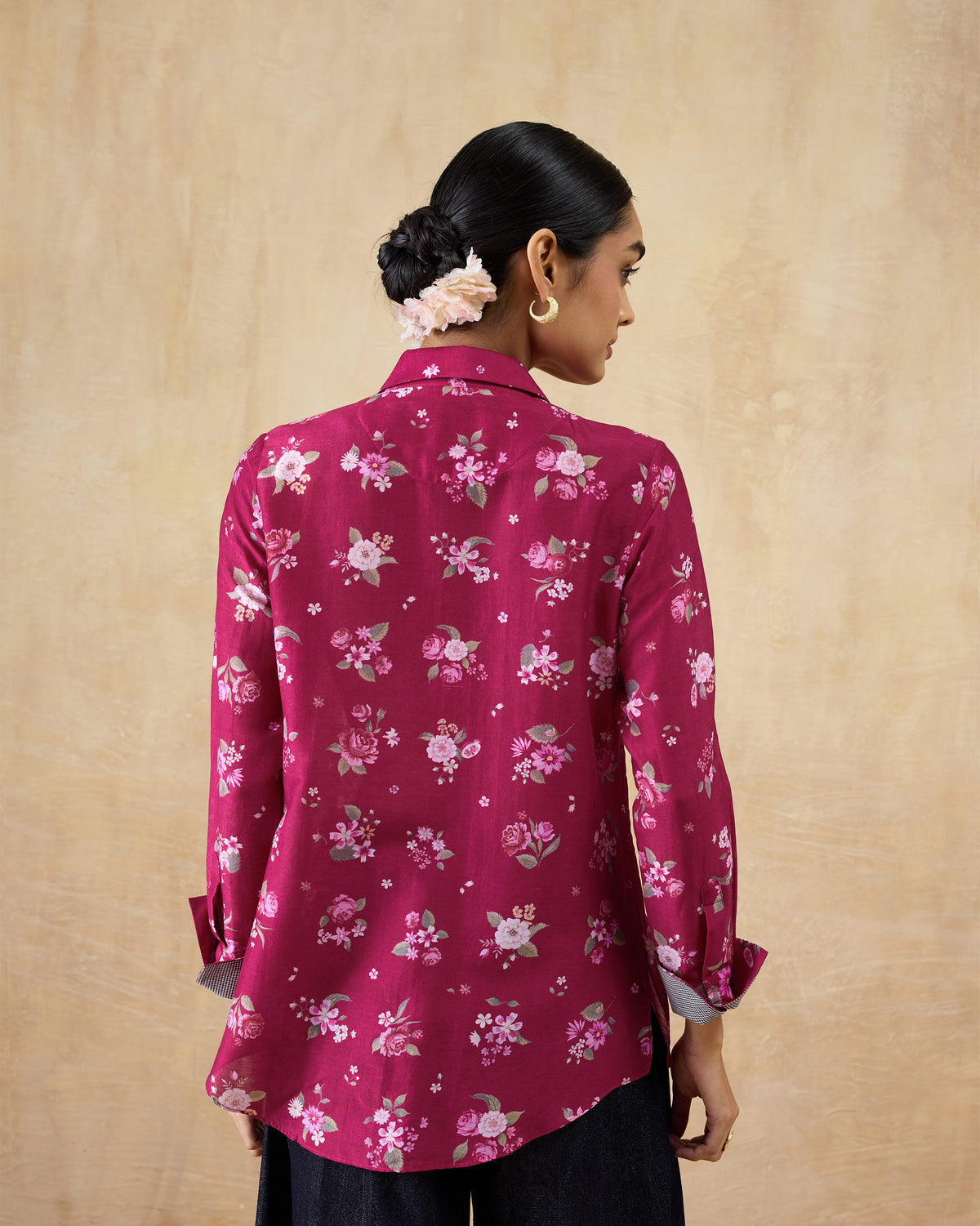 Back of a berry Kaveri ruffle shirt with a floral print and curved hem.