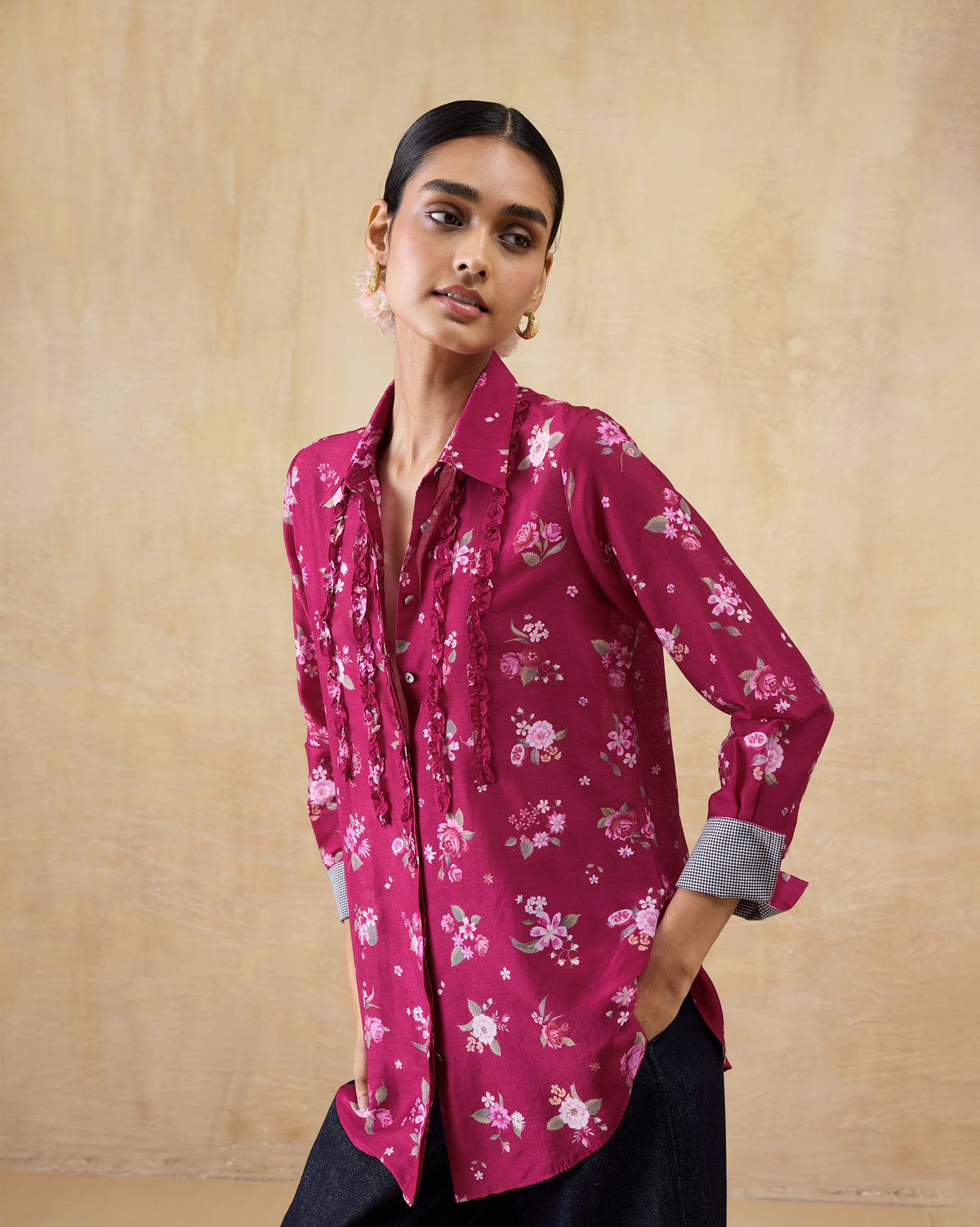 Person wearing a berry floral Kaveri ruffle shirt with rolled contrast cuffs.