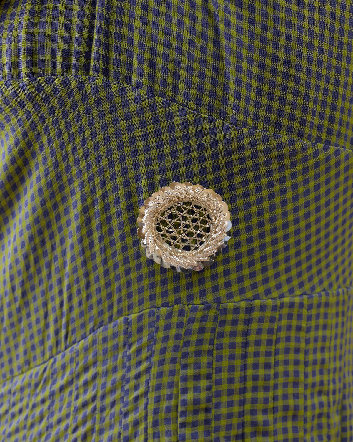 Close-up of a gold jali flower on a purple-and-lime check Kochi kurta.