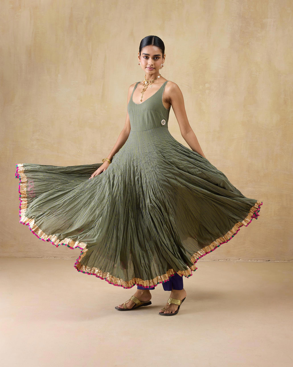 Person wearing a purple-and-lime check Kochi kurta with a flared skirt and gold hem.