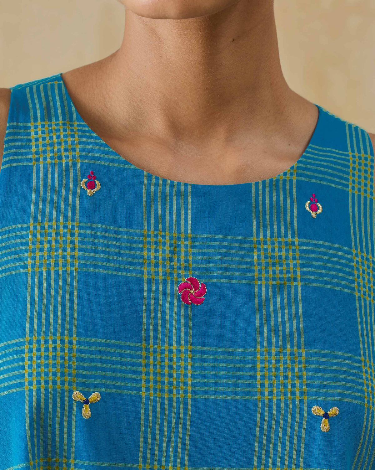 Close-up of floral embroidery on a cerulean check Nimbus dress neckline.