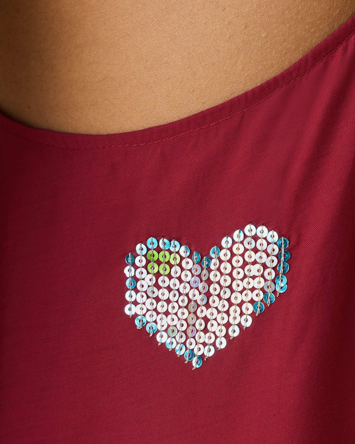 Close-up of a wine red Savni dress with a blue and gold sequin heart.