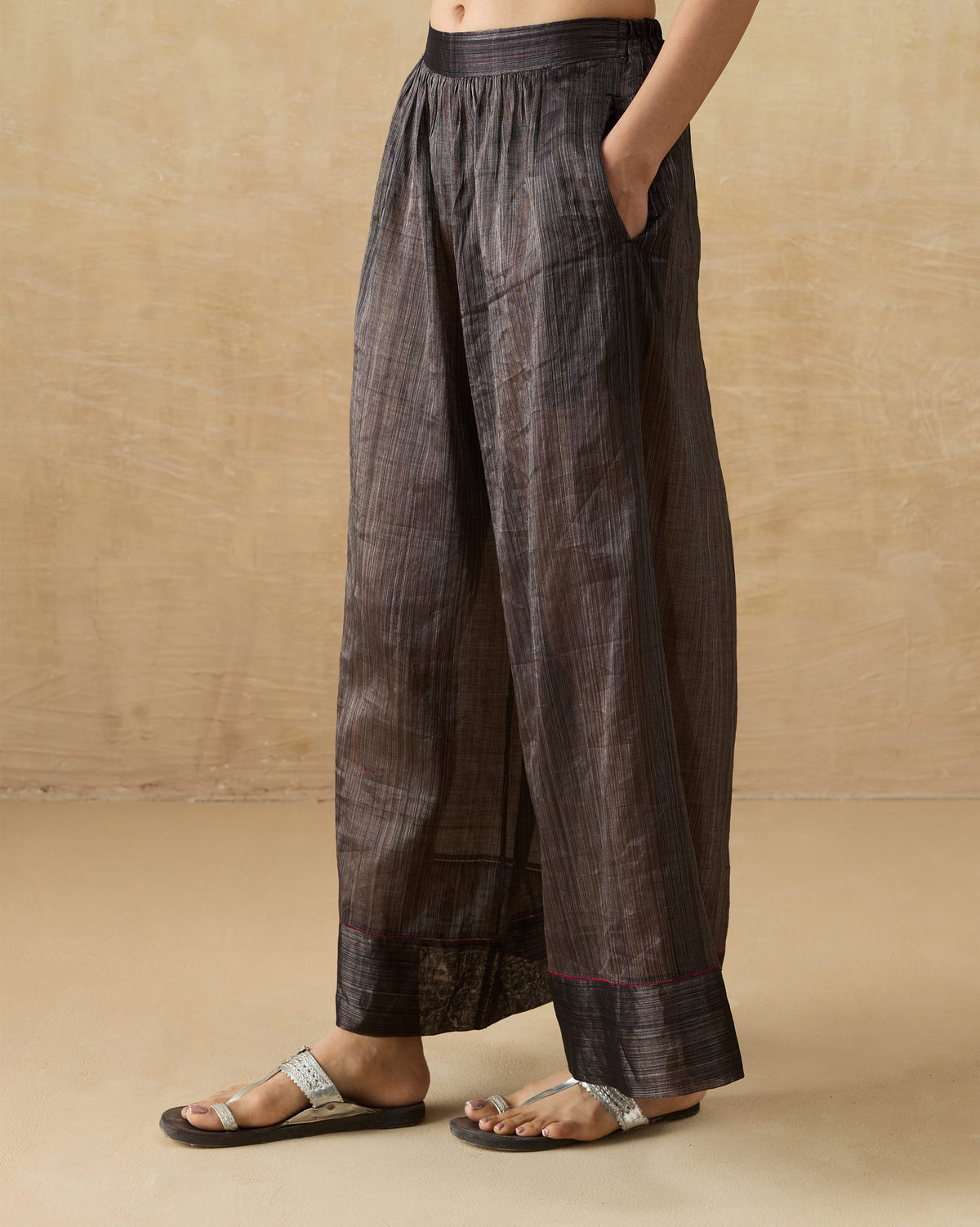 Side view of black metallic Charisma pants with a side pocket.