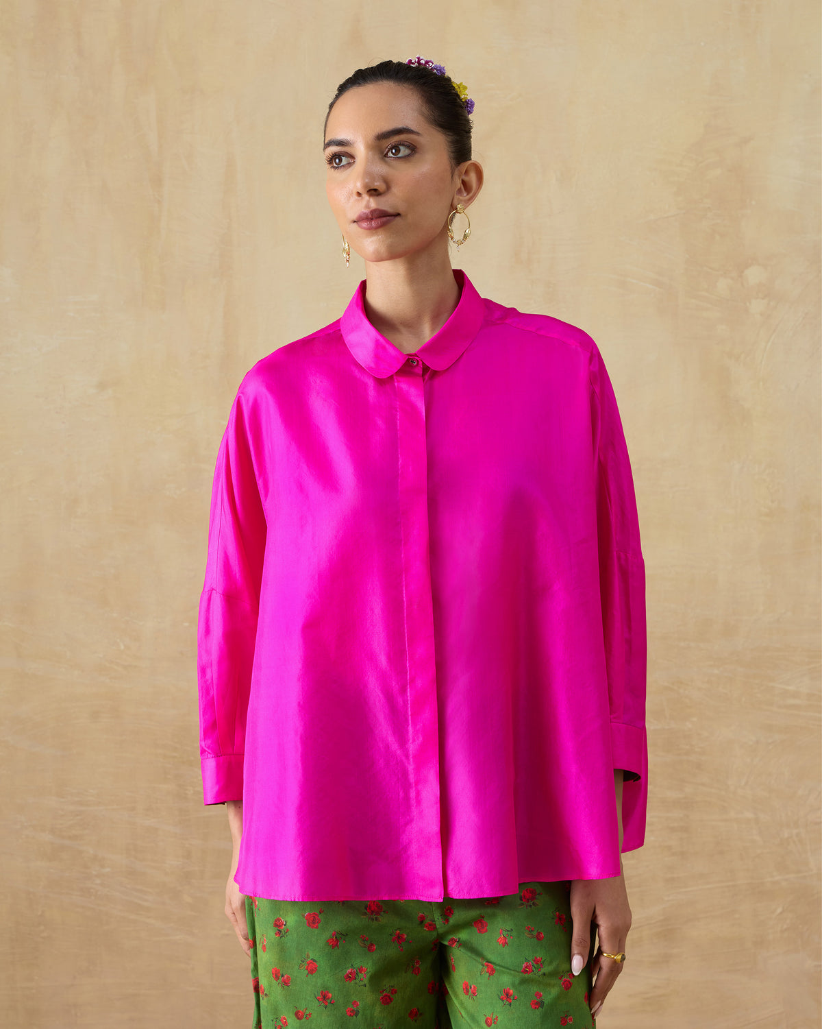 Person wearing a fuchsia pink silk boxy shirt with a rounded collar and concealed placket.