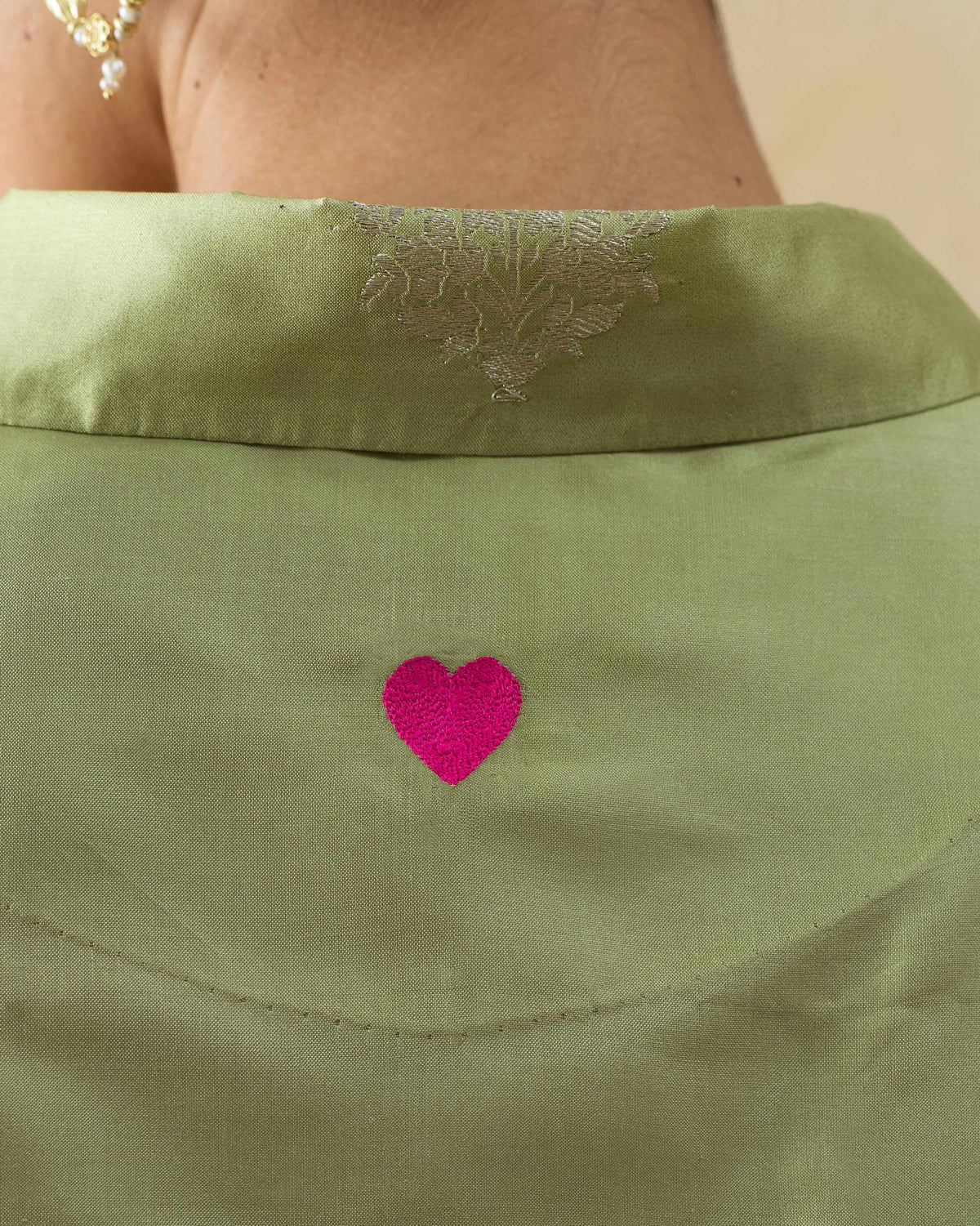 Close-up of a pink heart on the back of a leaf green Boxy shirt.