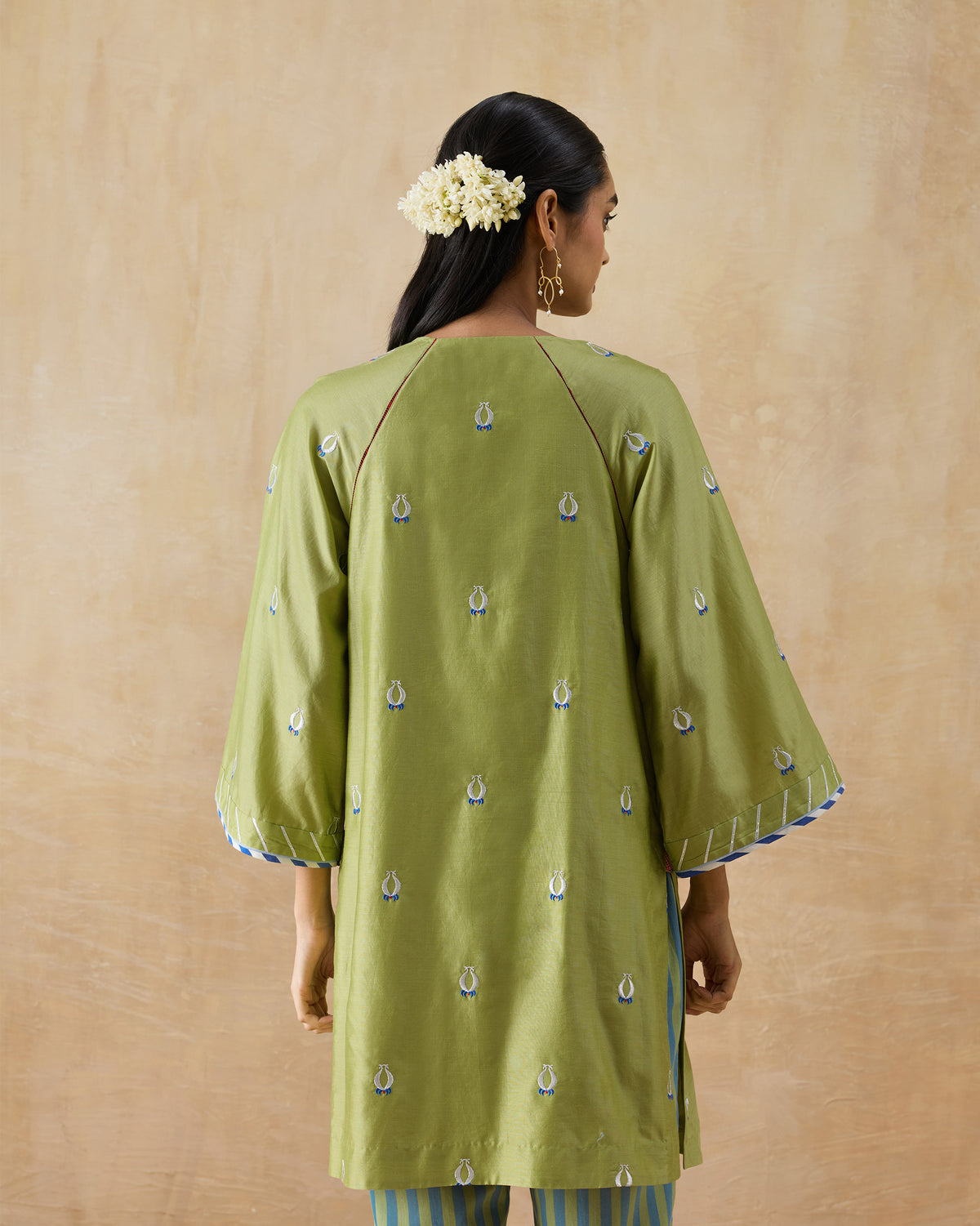 Back of an olive green Revelry kurta with white and blue embroidered motifs.