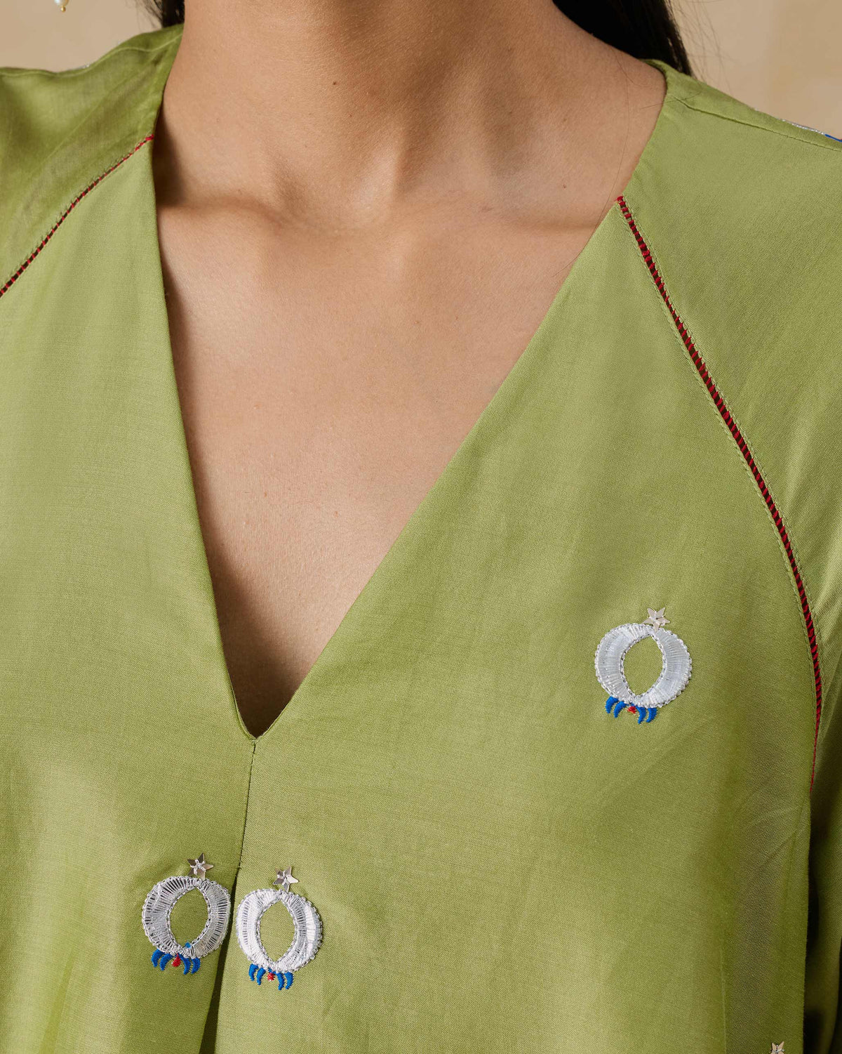 Close-up of the V-neck and embroidered motifs on the olive Revelry kurta.