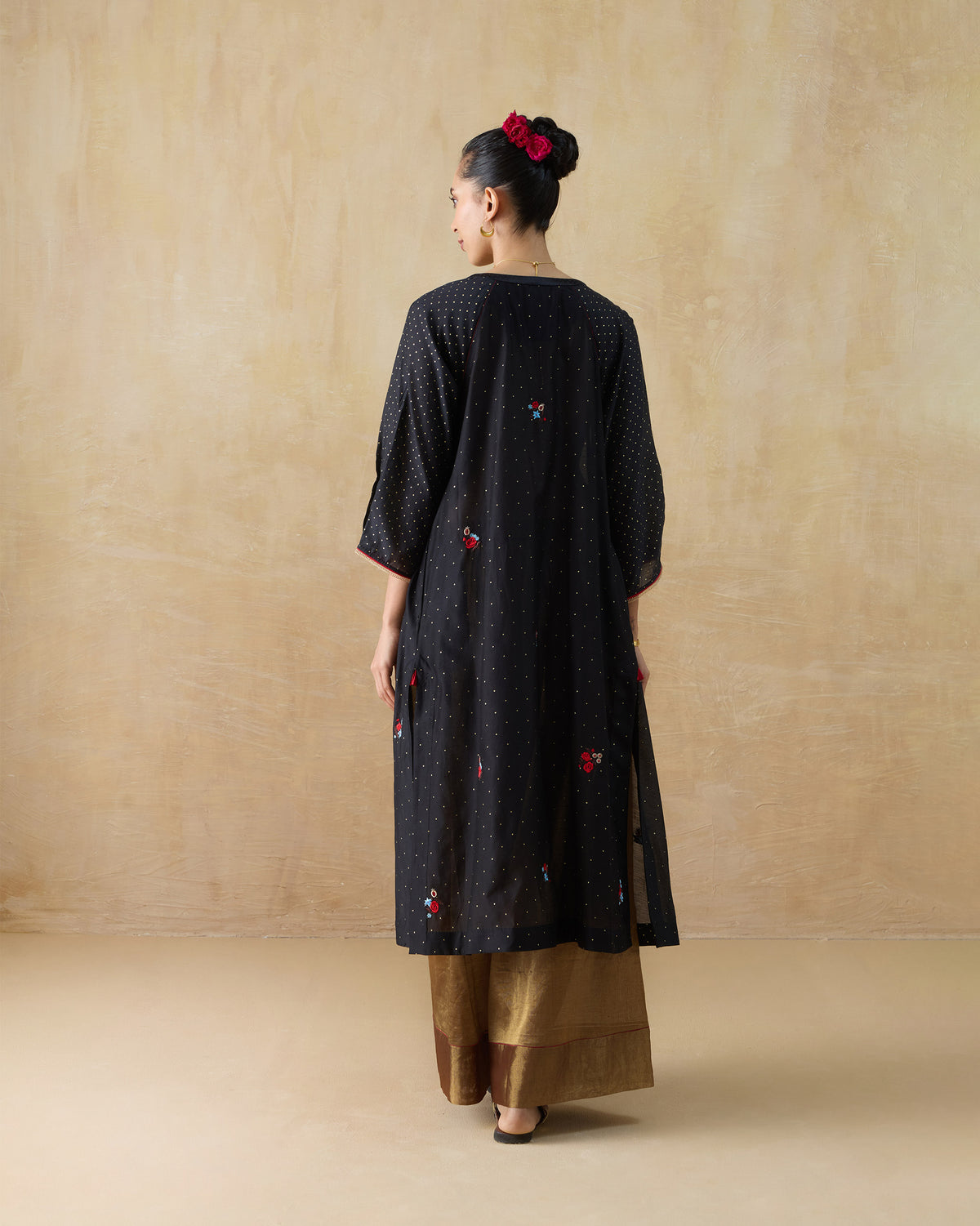 Back of a black Moonbeam kurta with gold dots and floral embroidery.