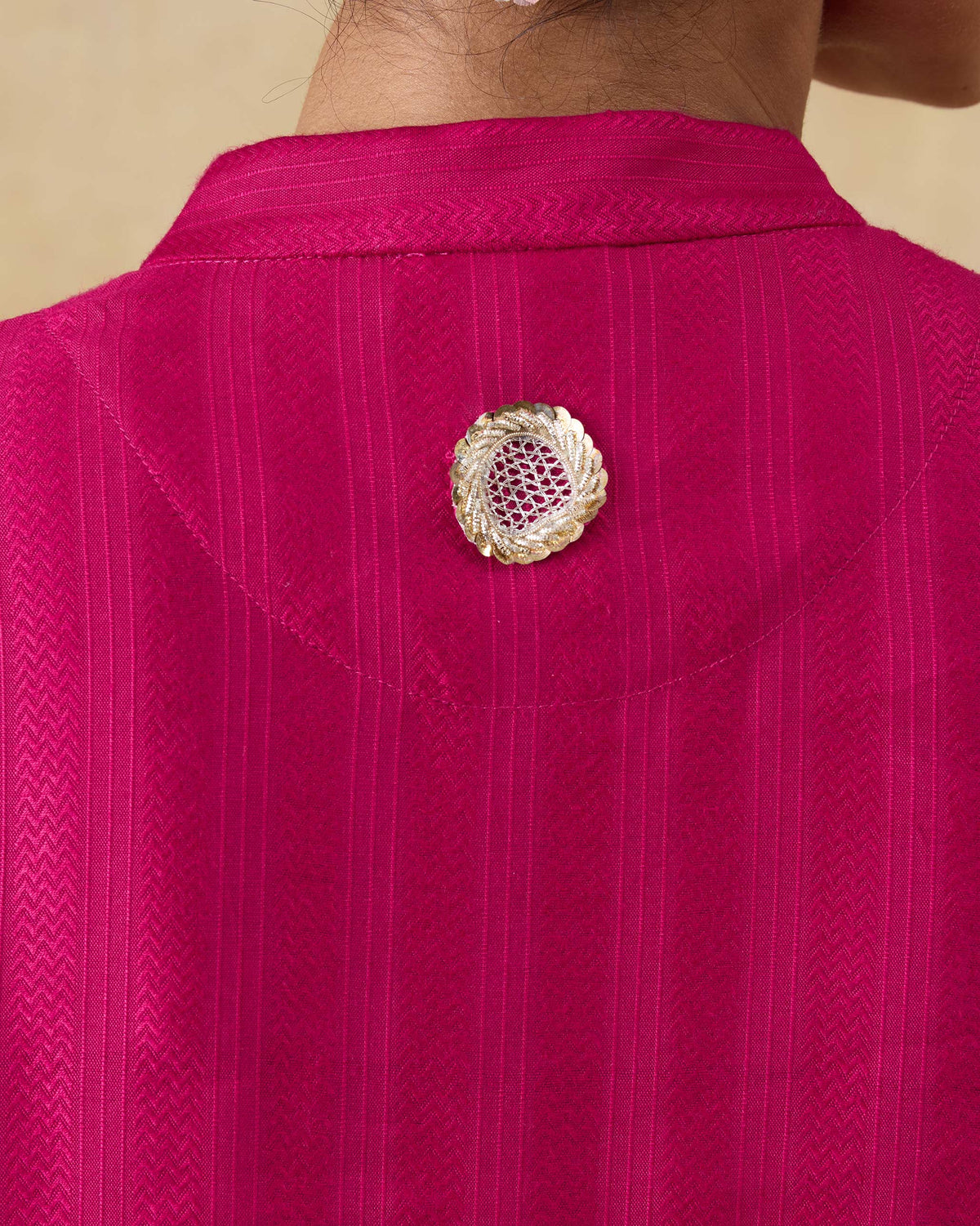 Close-up of a gold back motif on a berry pink mid length kurta.
