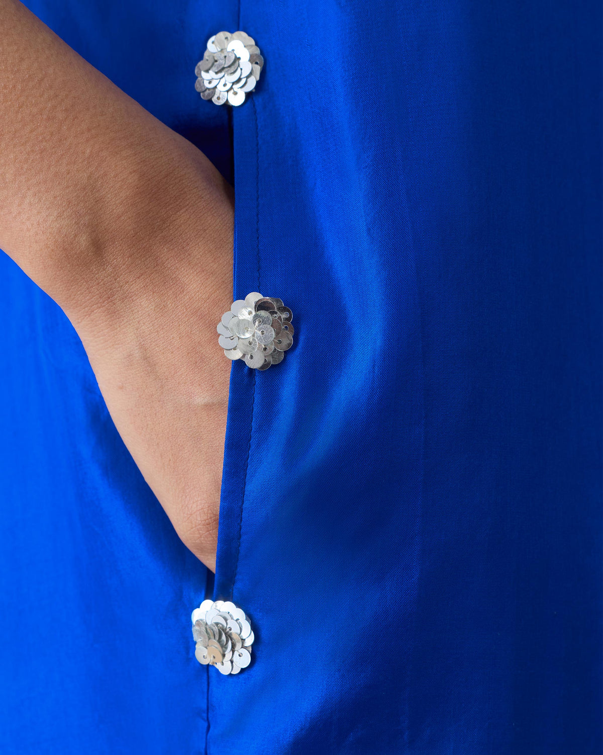Close-up of silver sequin rosettes on a cobalt Akira Twist Back Dress.