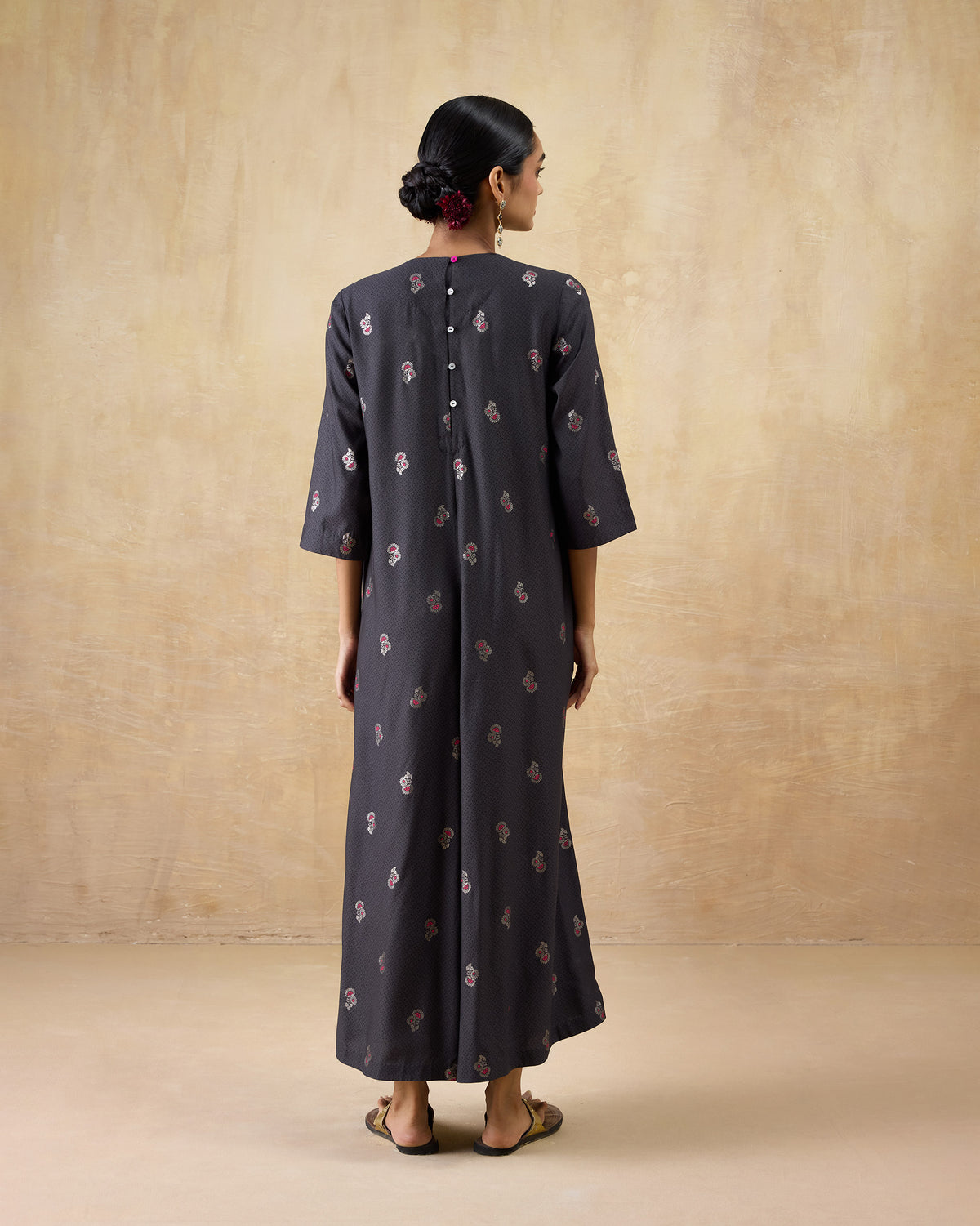 Back of a charcoal Bash jumpsuit with pink floral print and back buttons.