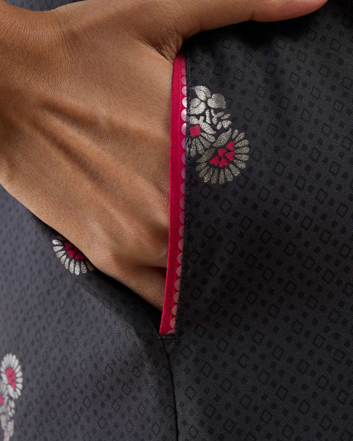 Close-up of a sequined pocket on a charcoal Bash jumpsuit with pink florals.