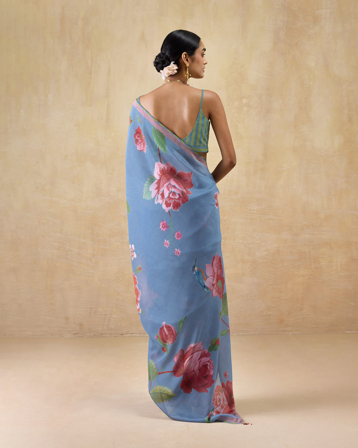 Person turned away in a blue First Bloom sari with a pink-edged border.