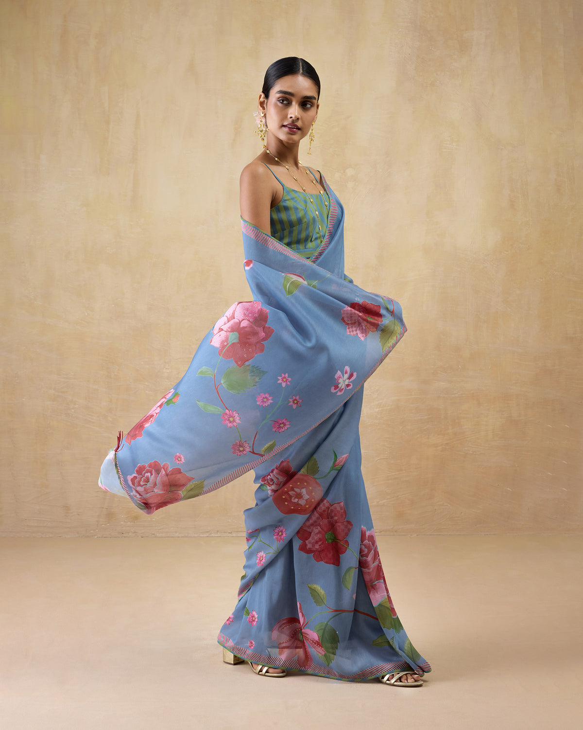 Person with a blue First Bloom sari draped over one arm, showing the pink rose print.
