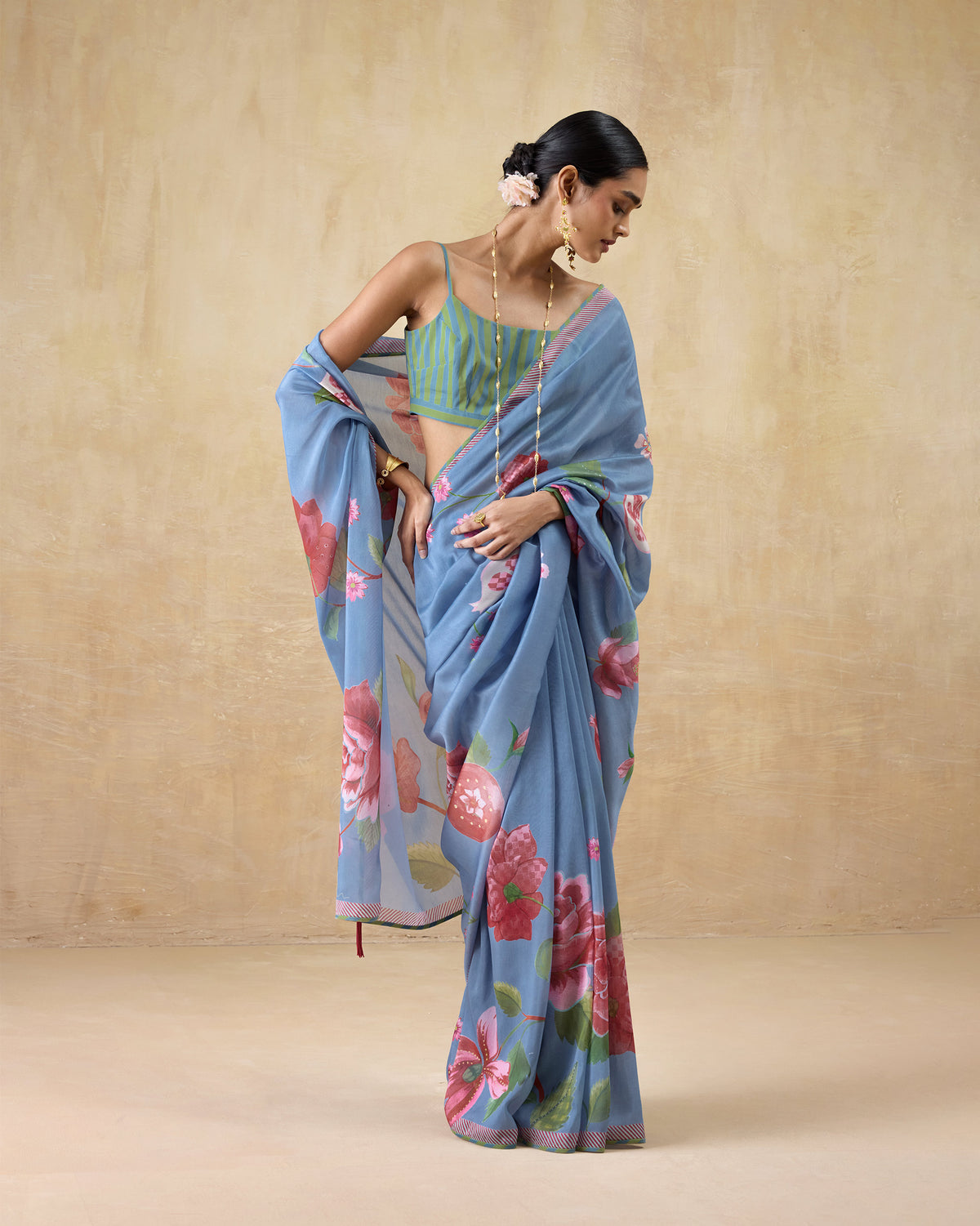 Person wearing a blue First Bloom sari with a pink rose print and a pink-edged border.