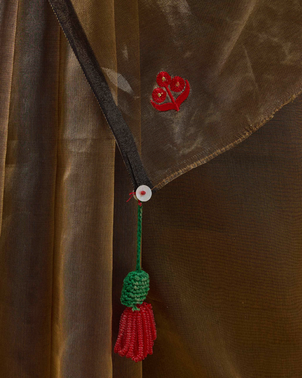 Close-up of a Dancefloor Sari corner with red embroidery and a tassel.