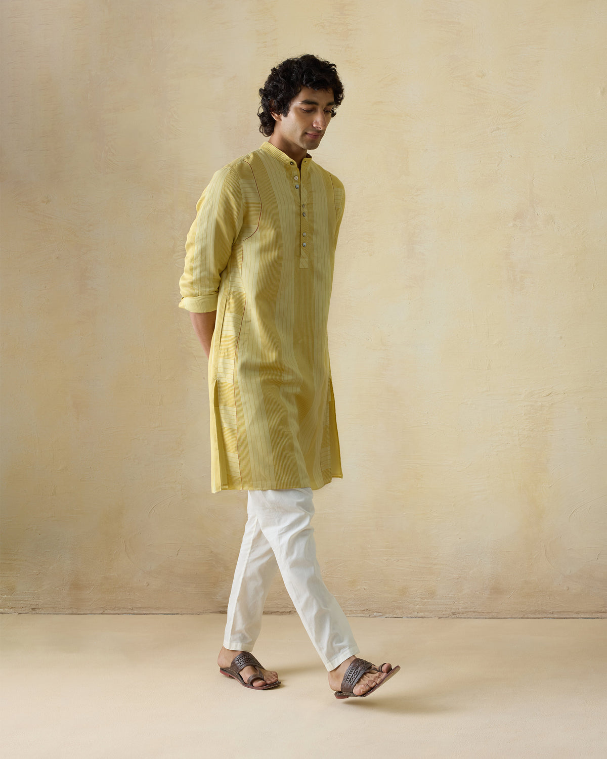 Person wearing a mustard and sage striped Voyage Kurta with band collar.