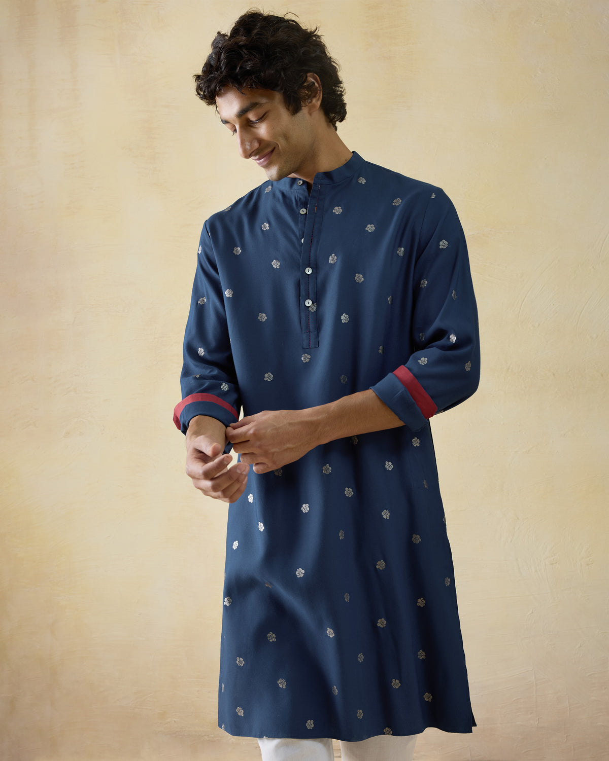 Person wearing a dark blue astral kurta with silver blooms and red cuff lining.