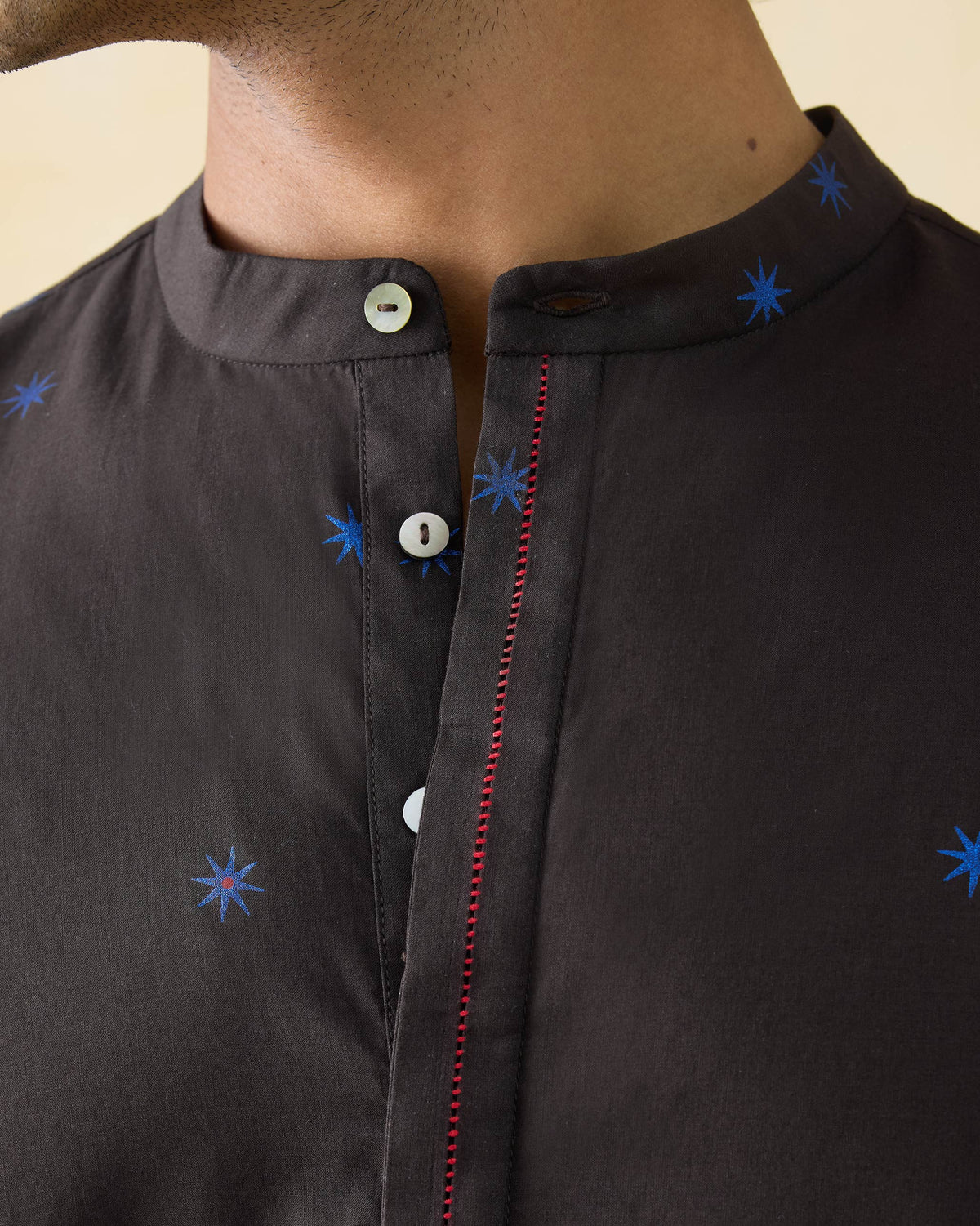 Close-up of a brown Gala Kurta showing blue star print and red placket stitch.