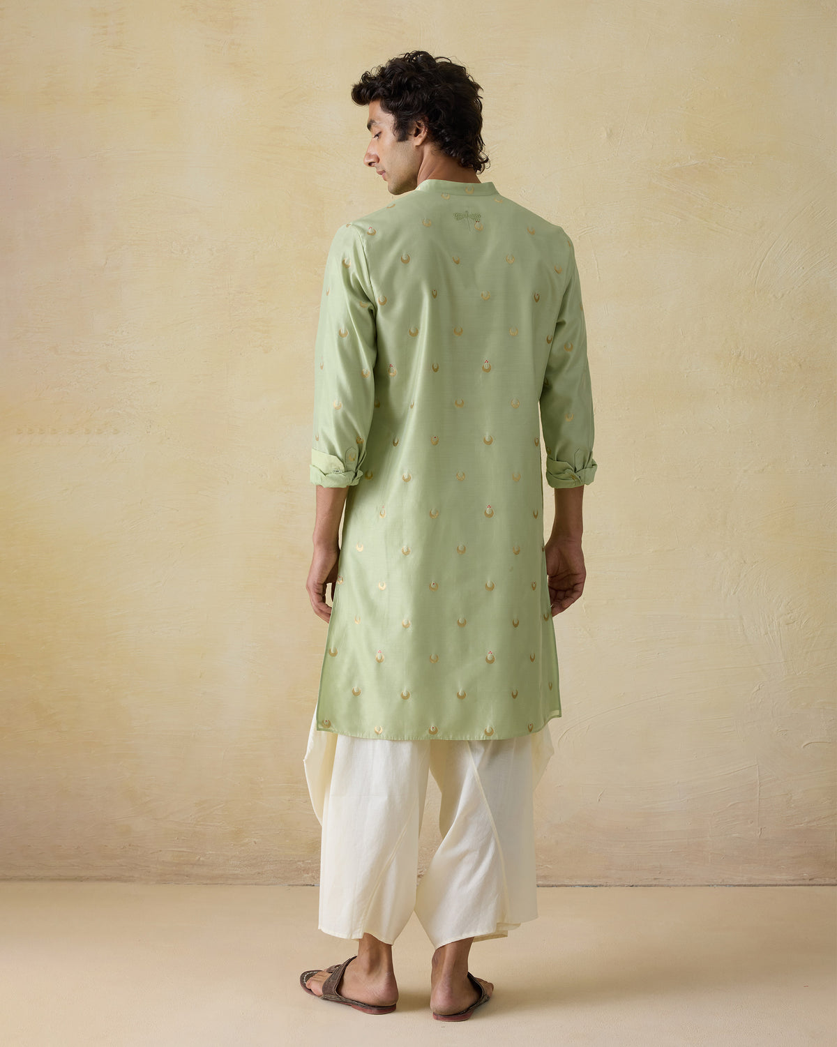 Back of a mint green astral kurta with gold valley motifs worn by a person.