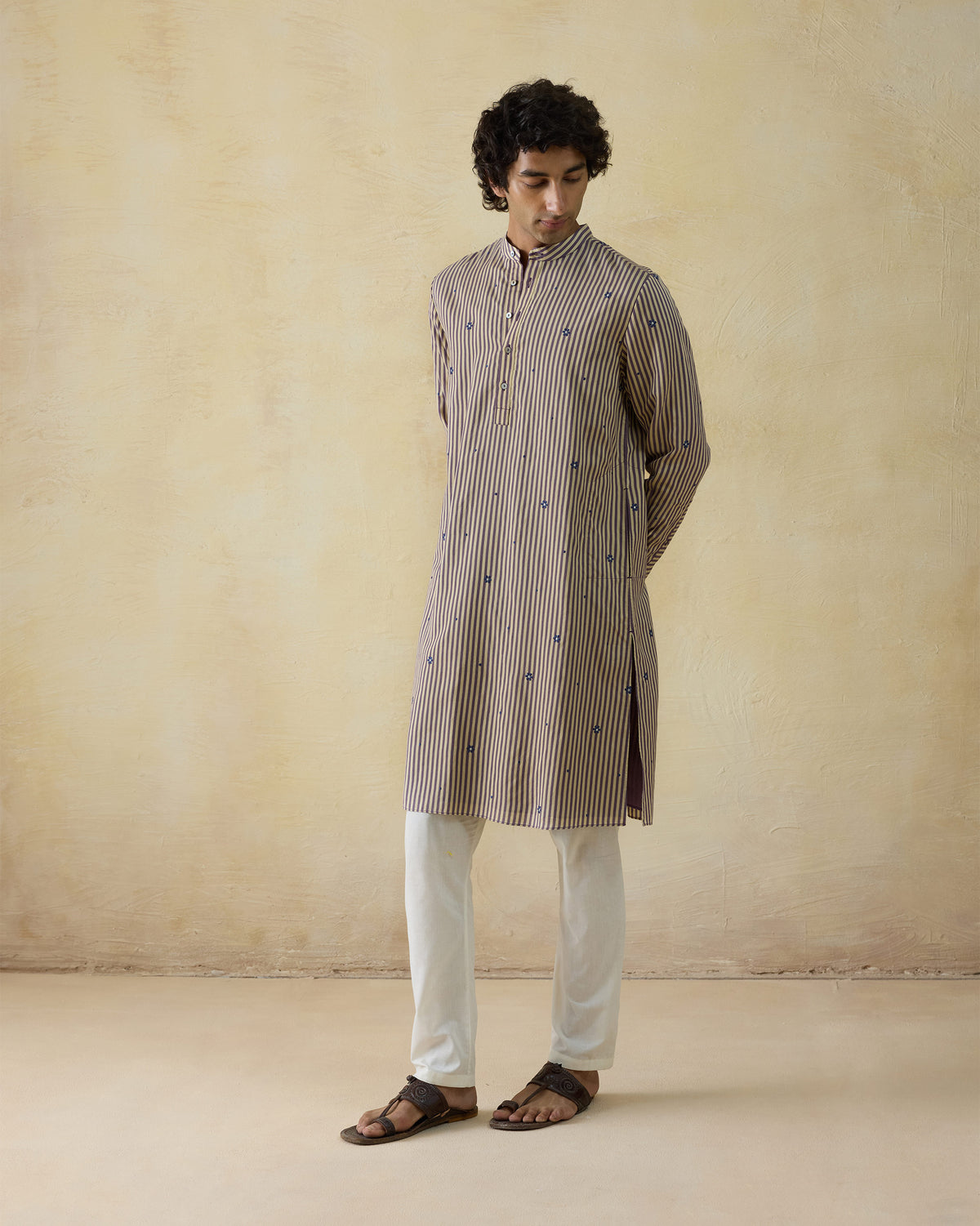 Person wearing a beige striped Shaam Kurta with blue embroidered motifs.