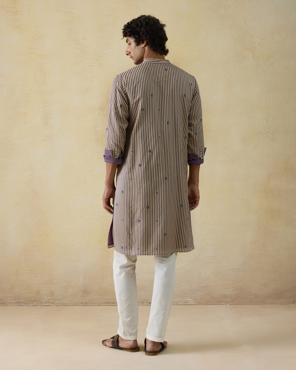 Back of a beige striped Shaam Kurta with blue motifs and plum cuff lining.