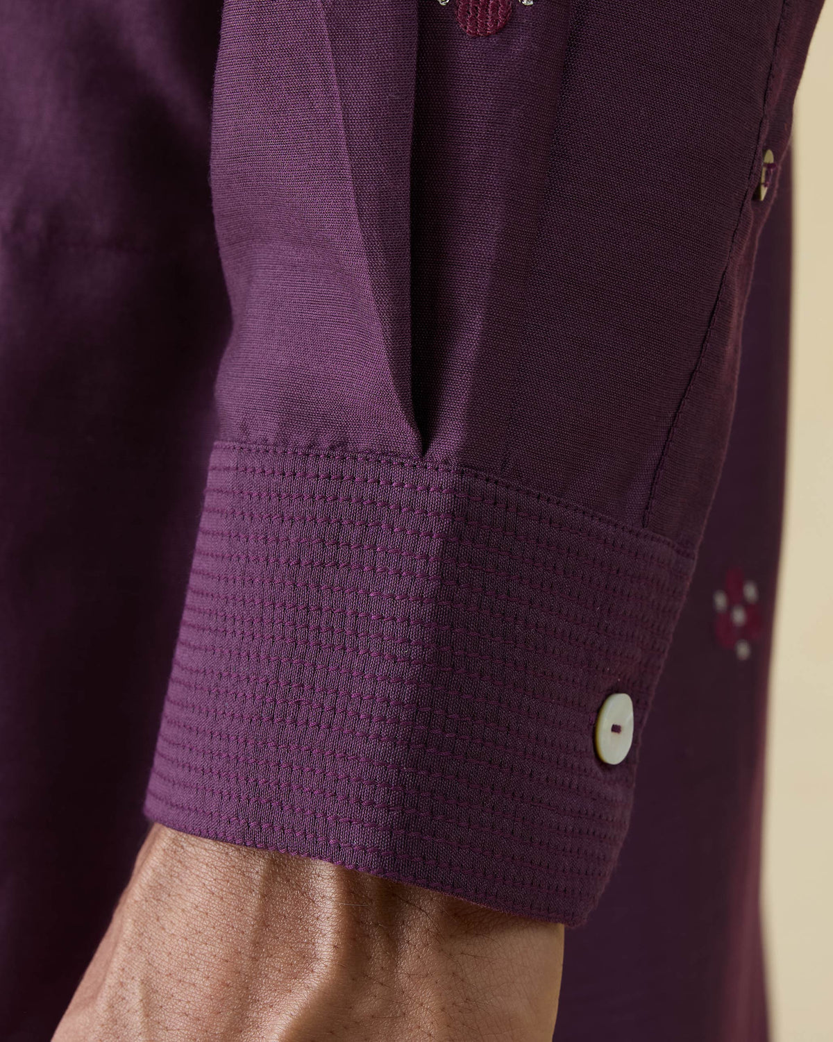 Close-up of a jamun pink Neckband Kurta cuff with tonal stitching and embroidery.