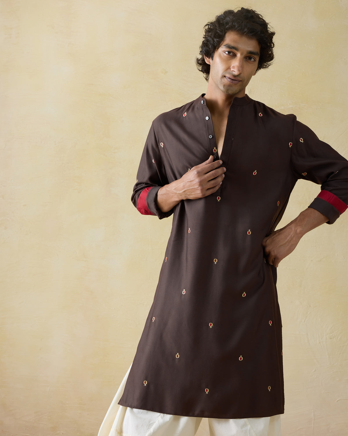 Person wearing a dark brown neckband kurta with pomegranate embroidery.