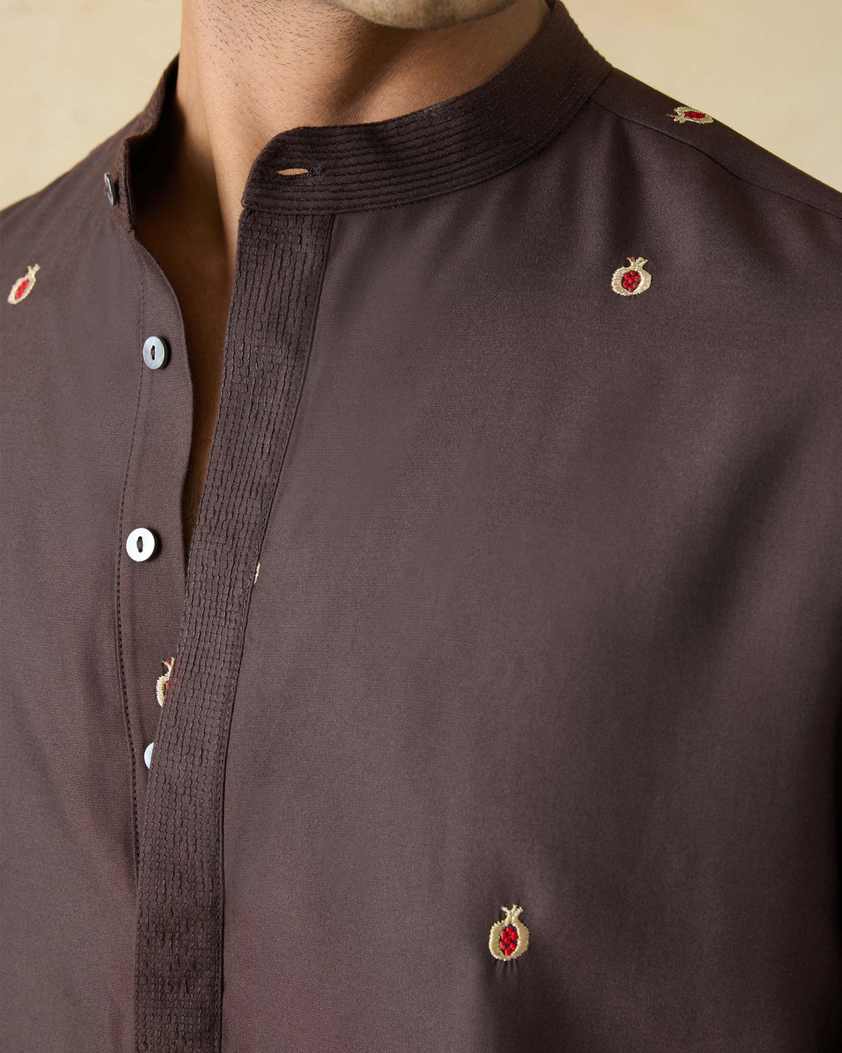 Close-up of a dark brown neckband kurta showing pomegranate embroidery.